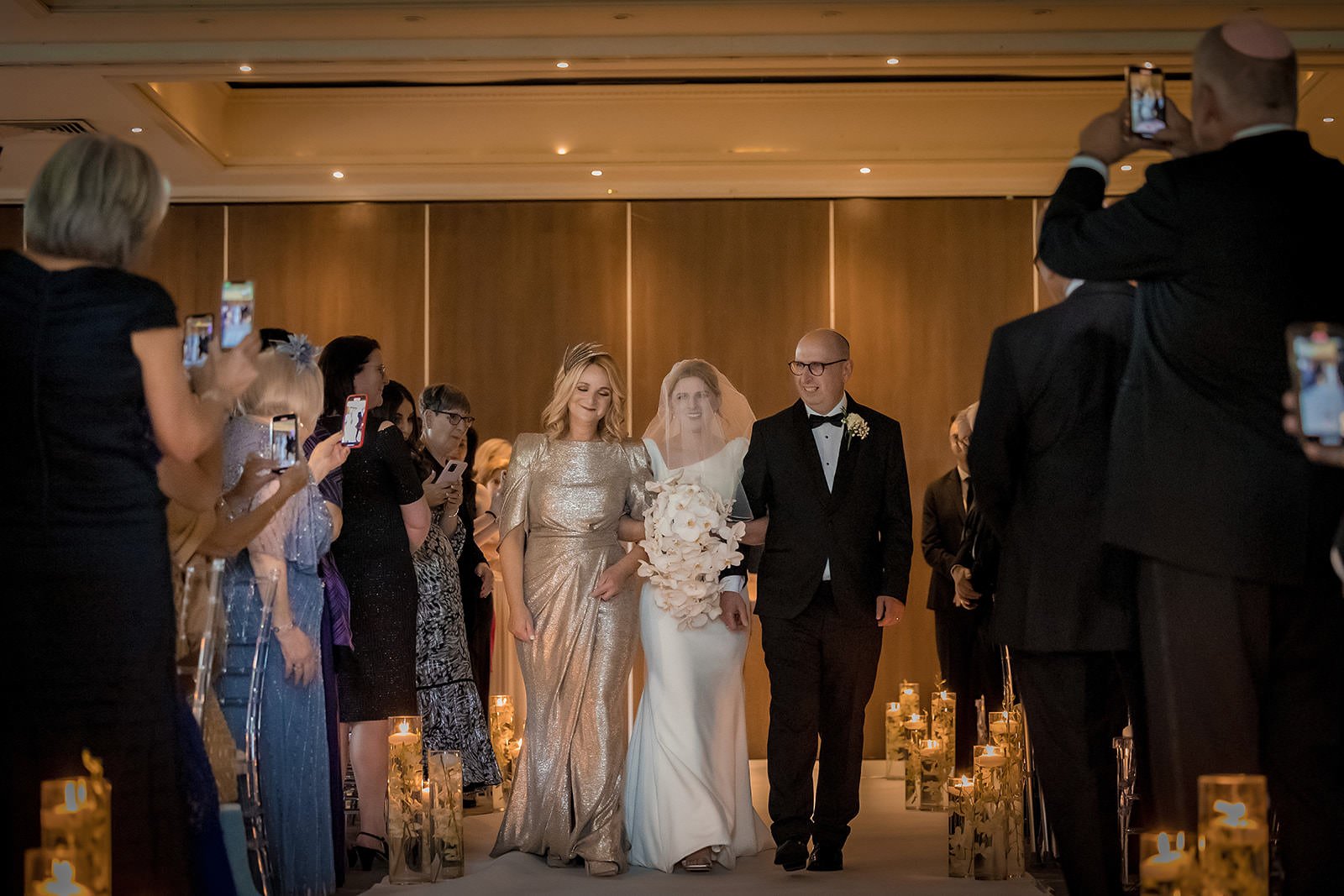 Bride walking down the aisle toward floral arch, The Mere Knutsford
