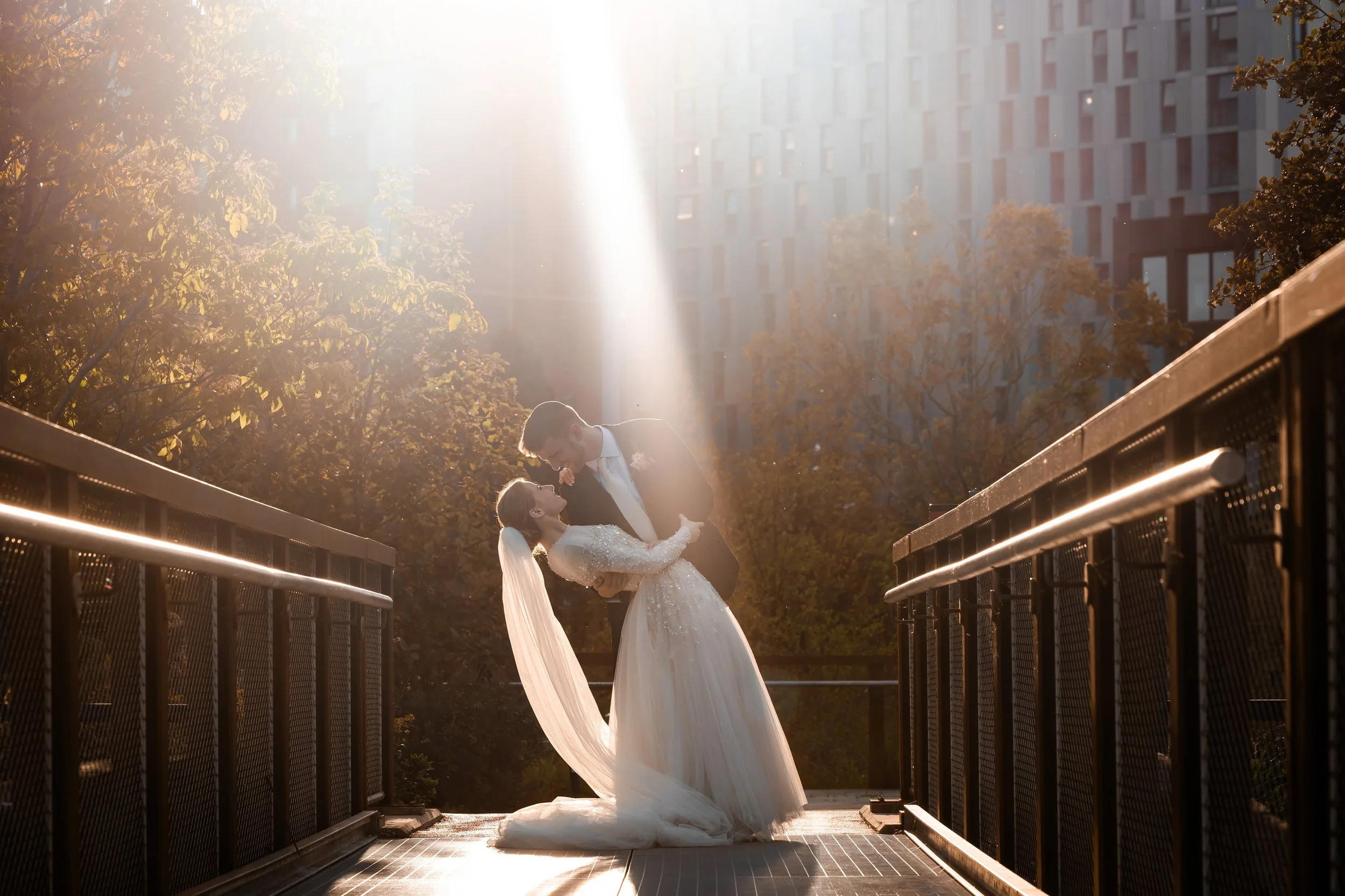 newlywed couple bride and groom kiss under beam of sunlight in manchester city center Mayfield gardens