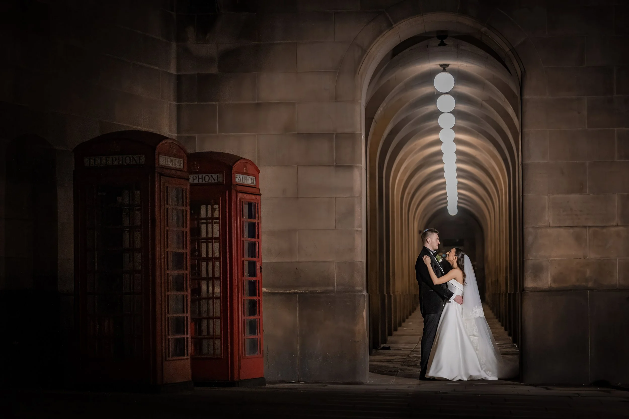 bride and groom newlywed couple portrait with arches and red phone booths in manchester city center
