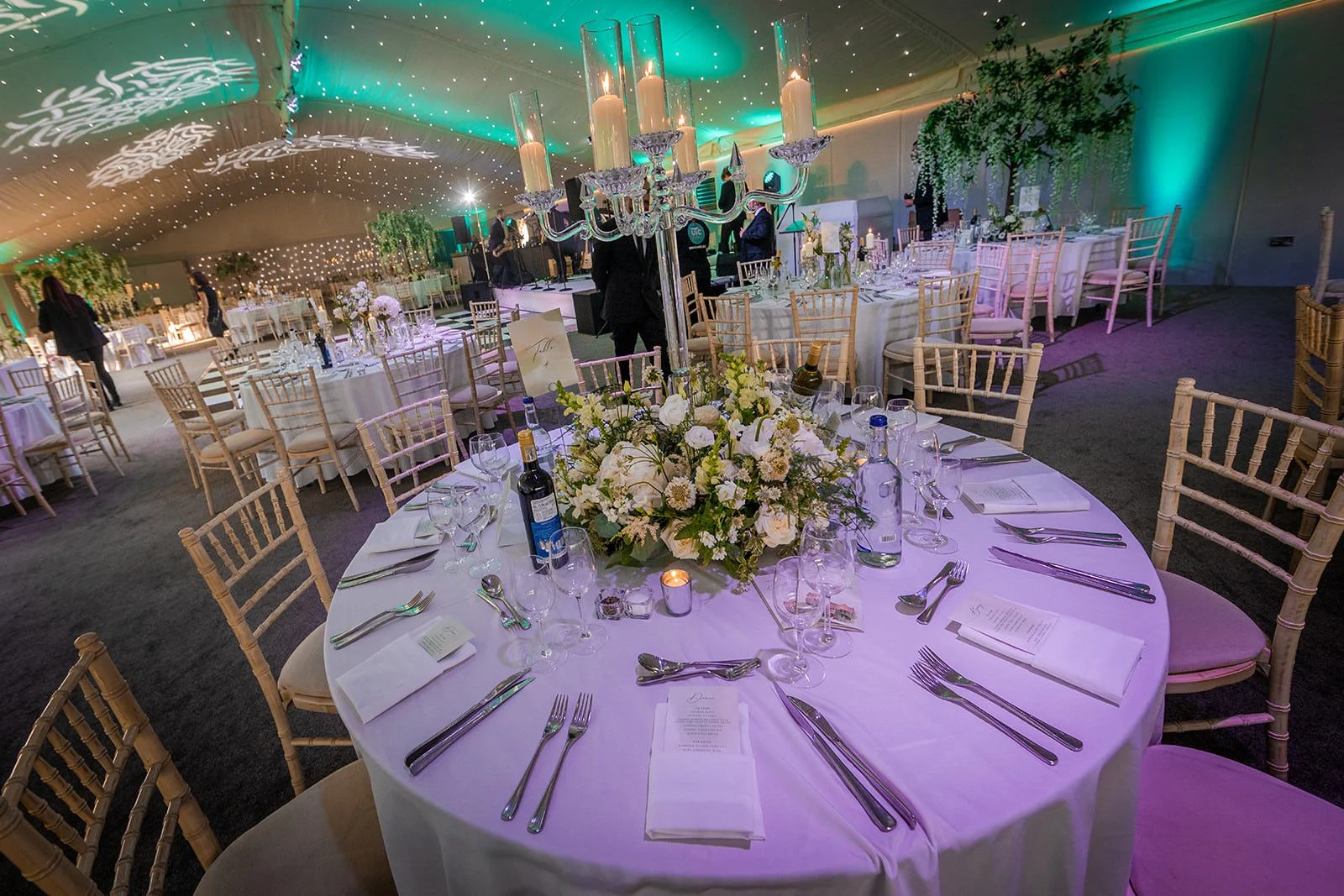 Candlelit table setting with floral centrepiece in Nunsmere Hall wedding marquee
