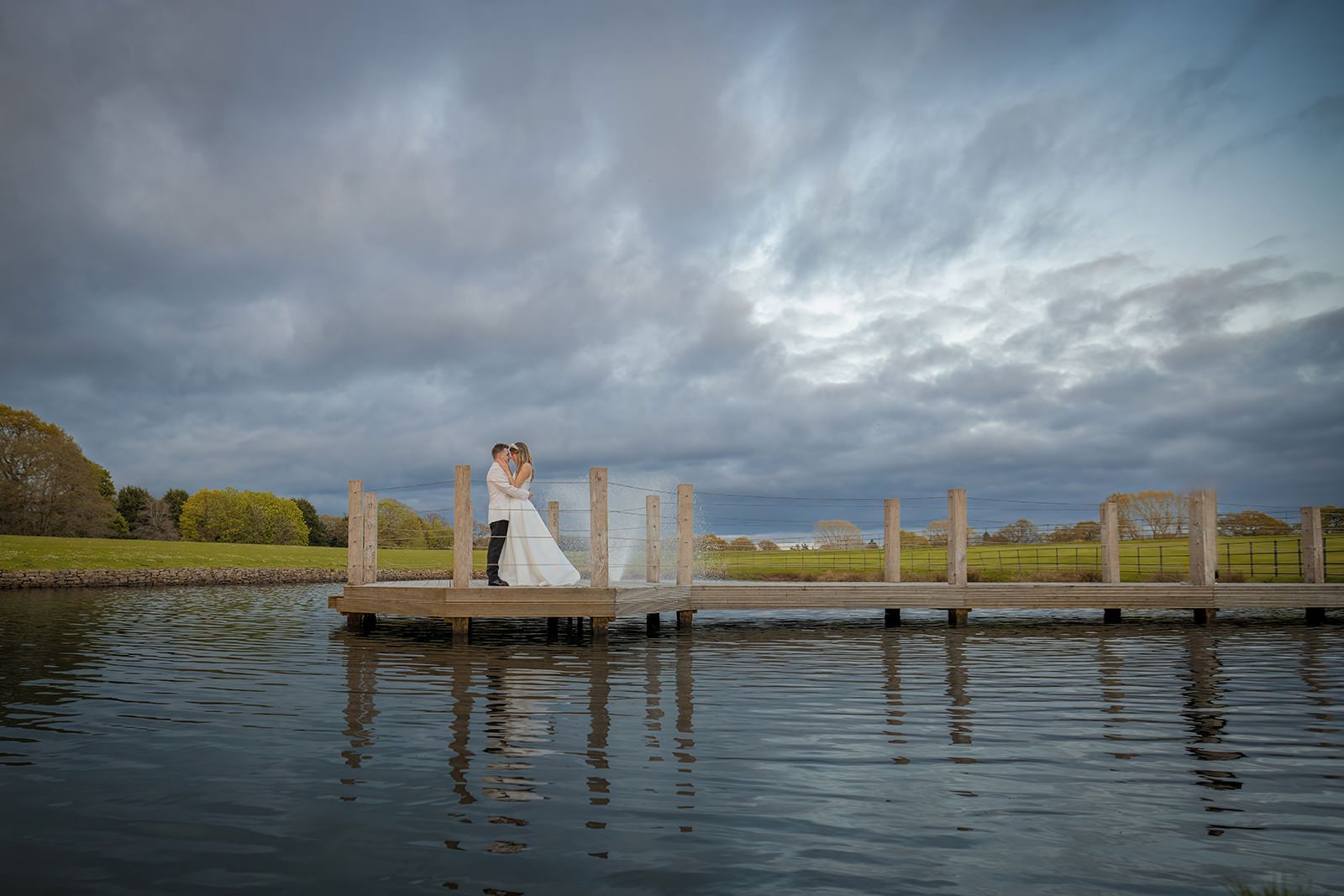 Bride and groom couple portraits on the jetty at Merrydale Manor with dramatic cloudy sky