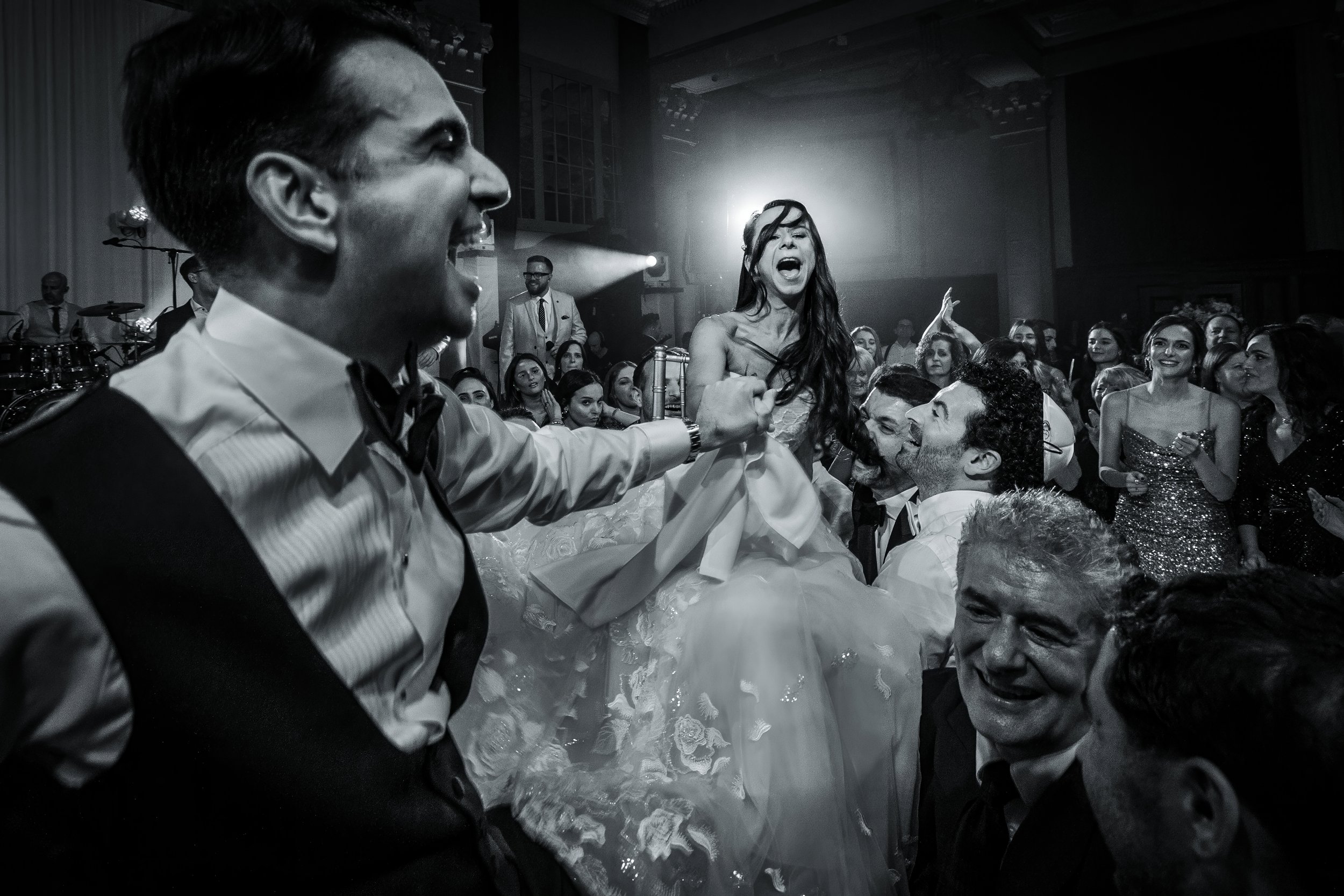 documentary action photograph of bride and groom lifted on chairs on dancefloor