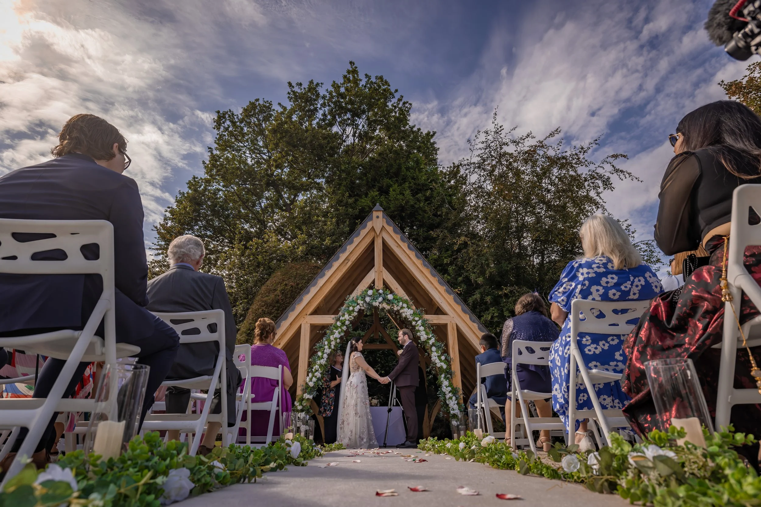Bride and groom hold holds during outdoor wedding ceremony