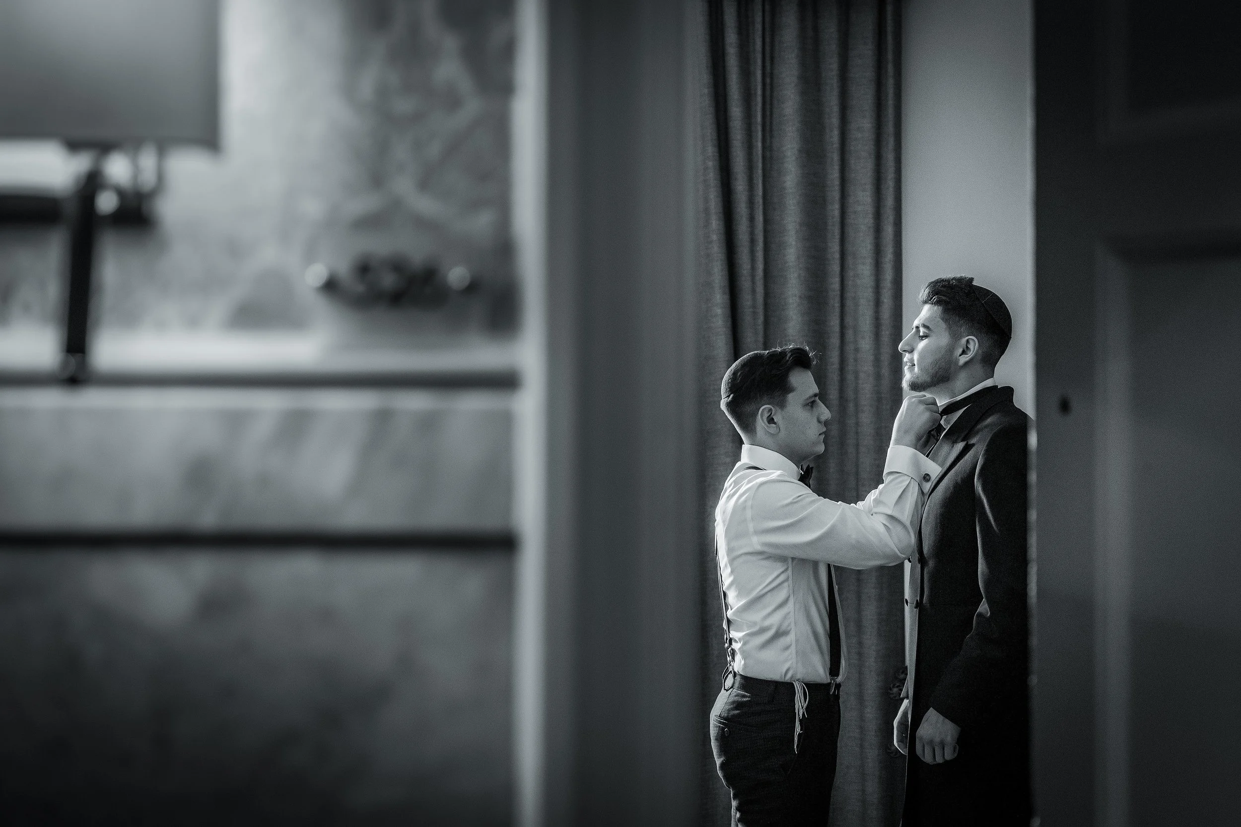 jewish wedding photography Manchester as groom gets help during prep from best man