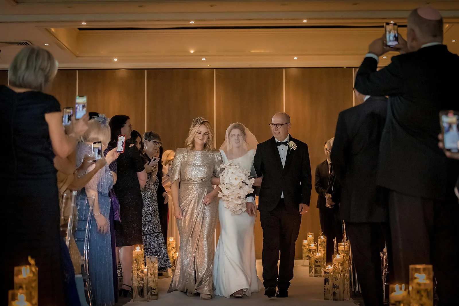 Bride's processional down candlelit aisle, guests watching, The Mere ceremony suite
