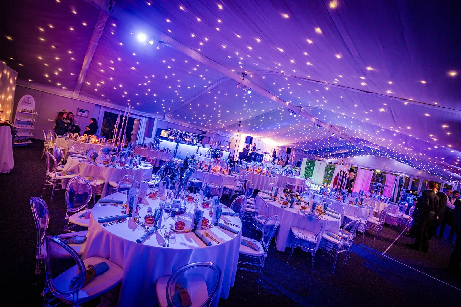Nunsmere Hall marquee set for dinner under starlit ceiling, blue lighting

