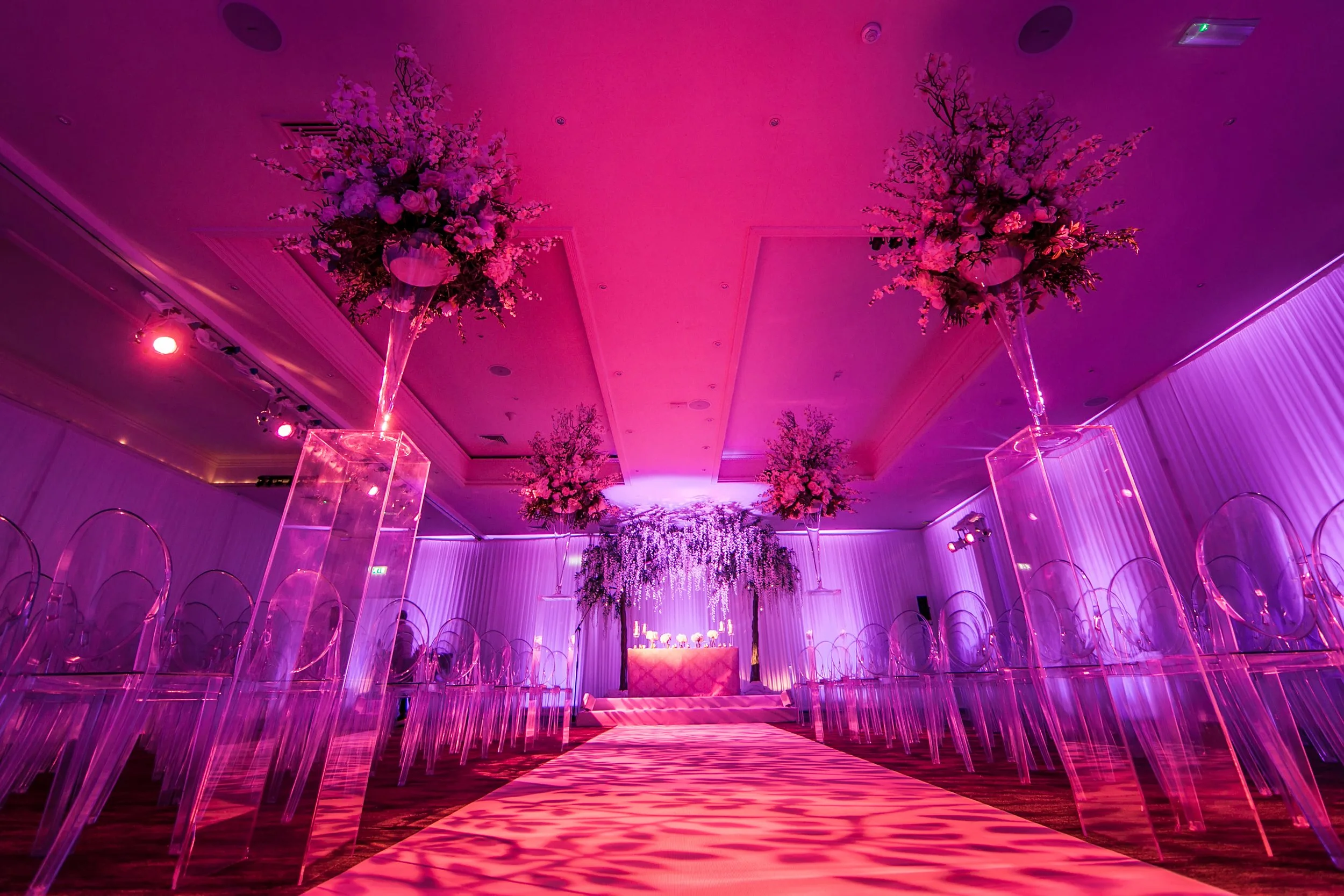Ceremony room with pink uplighting and floral columns, Fairmont Cheshire - The Mere
