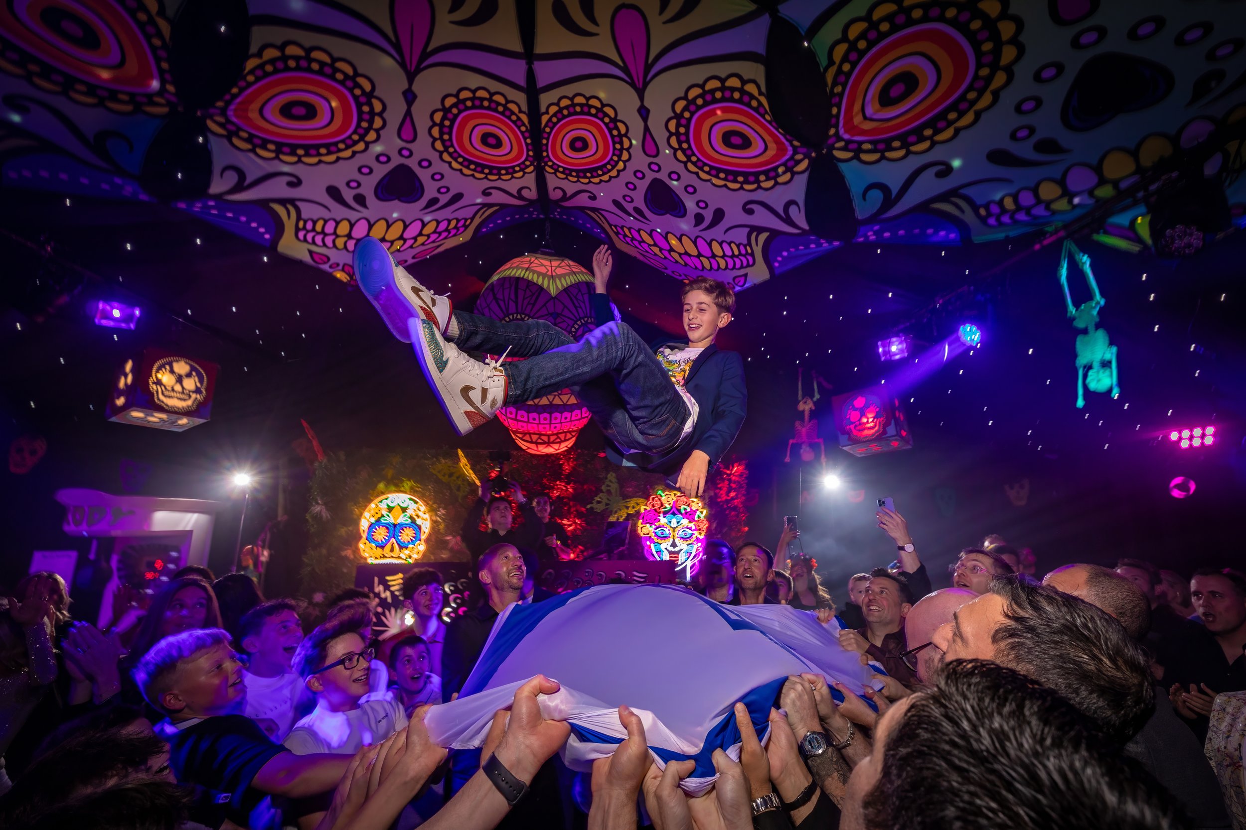 barmitzvah boy thrown high into air on a sheet by guests during party dance floor celebrations in Manchester