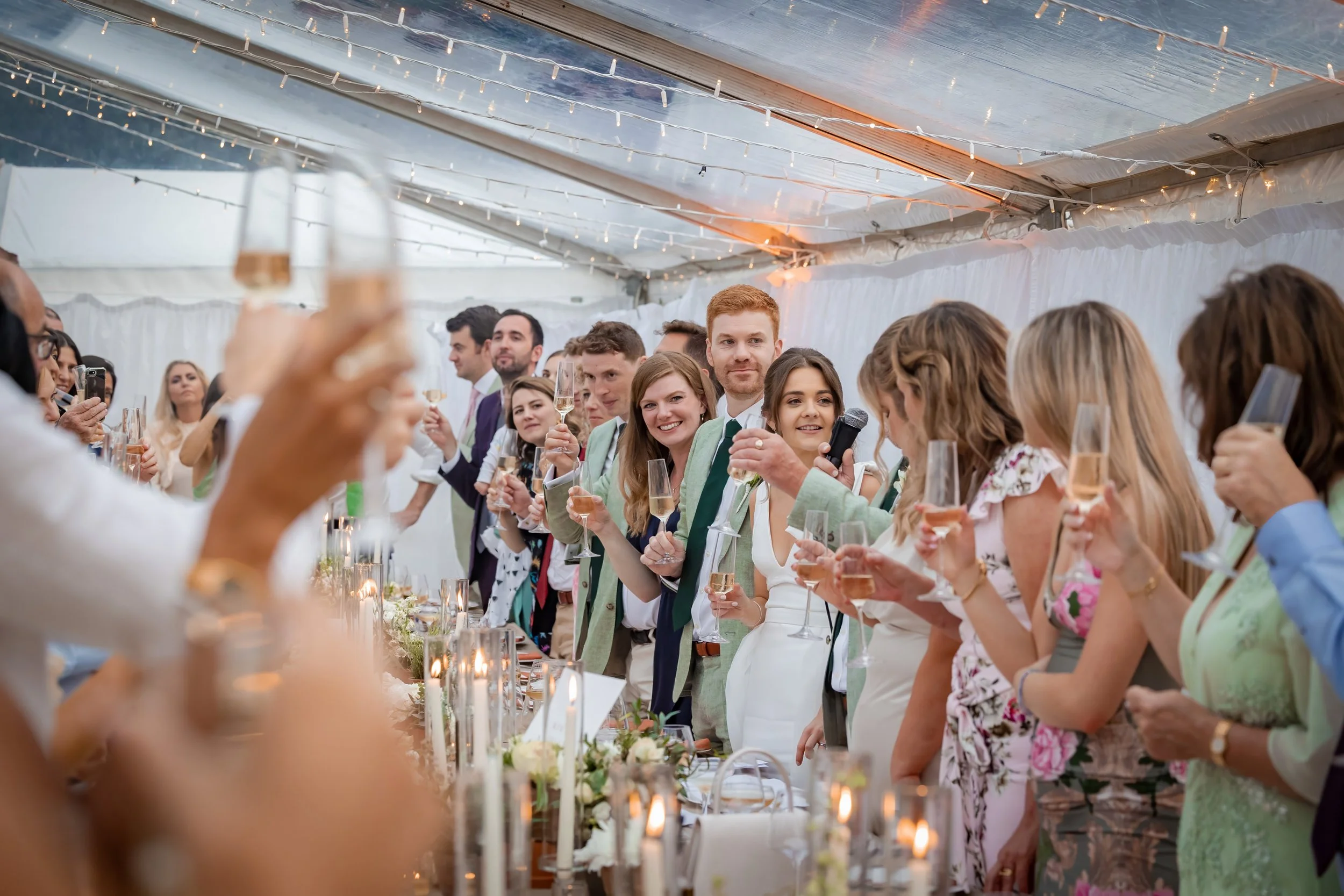 Bride and groom and guests toast wedding speeches in a marquee in Manchester