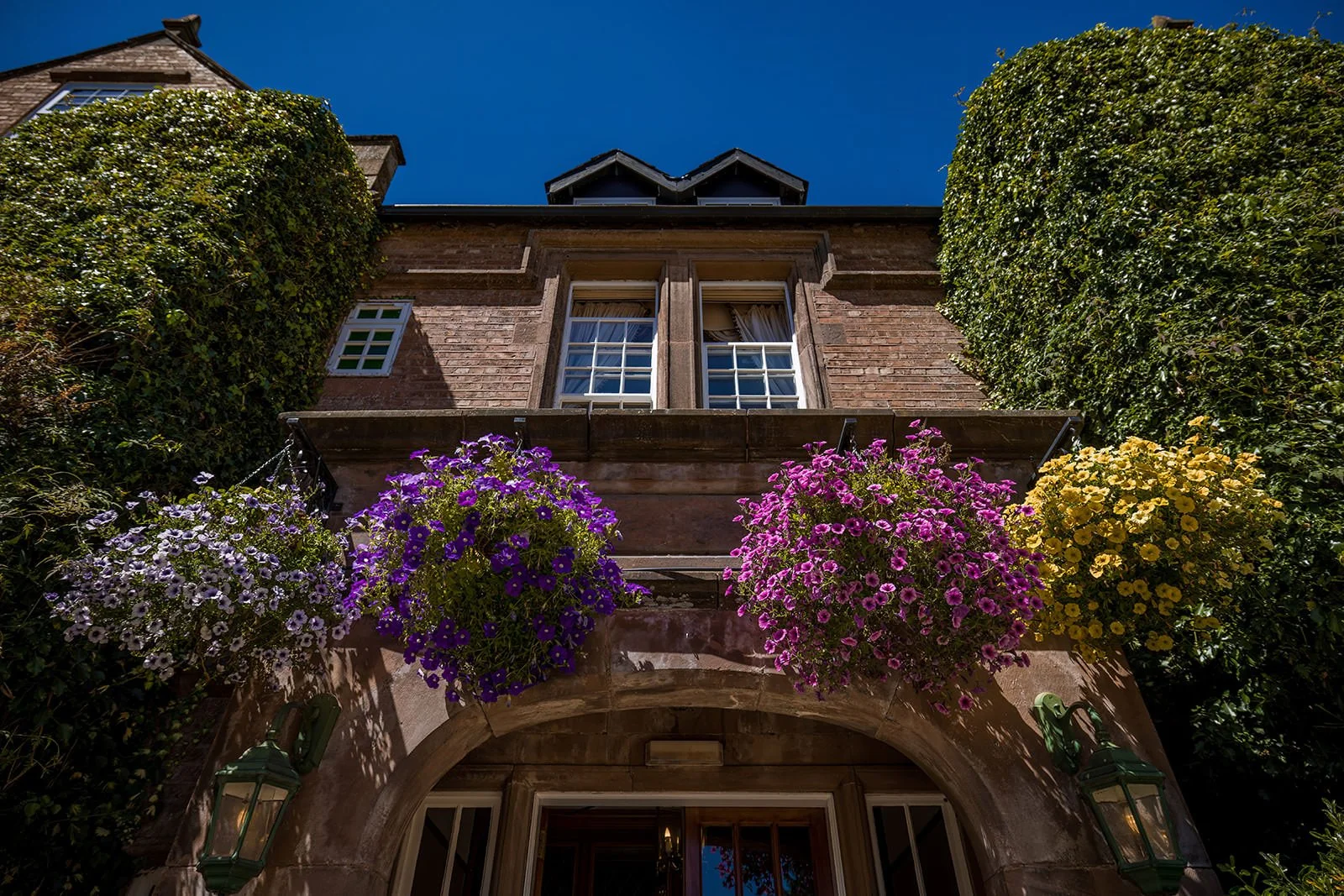 Nunsmere Hall red brick exterior with flowering wisteria, summer wedding venue Cheshire
