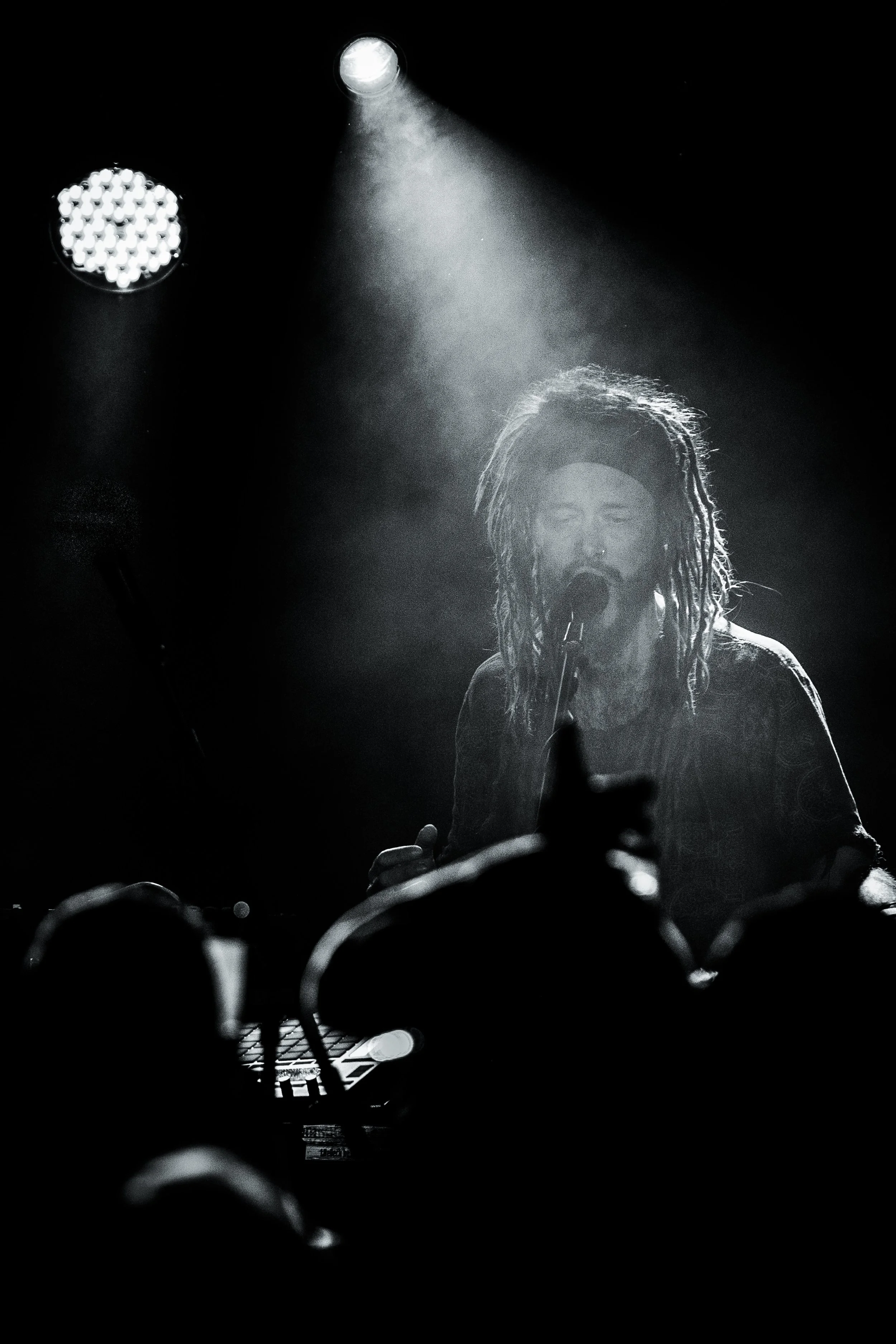 Musician MC Xander performing live on stage in dramatic black and white