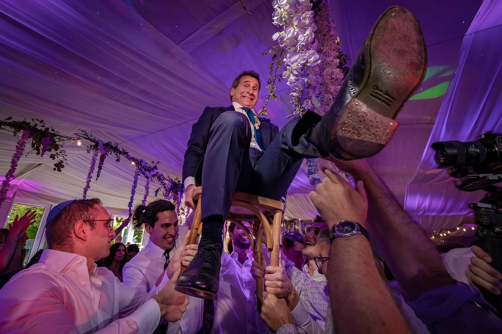 father of bride lifted on chair during wedding evening reception at nunsmere hall venue in cheshire