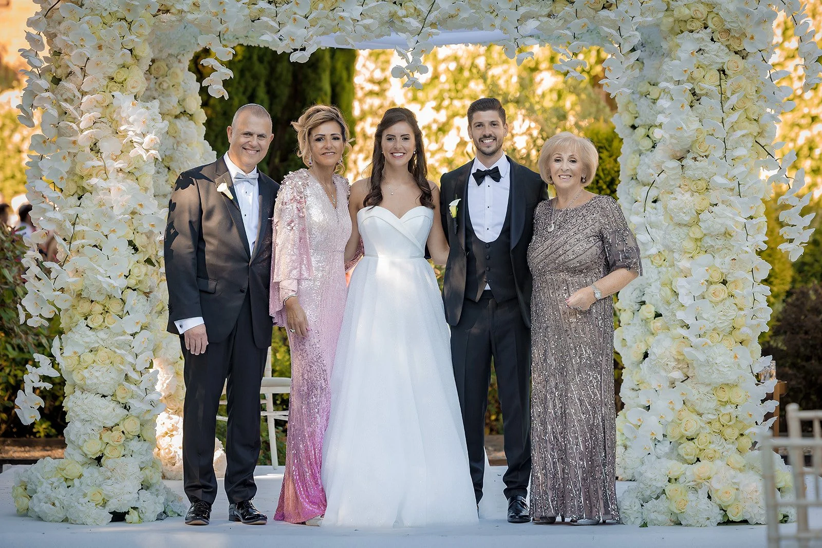 Small family group portrait in front of floral arch at Nunsmere Hall

