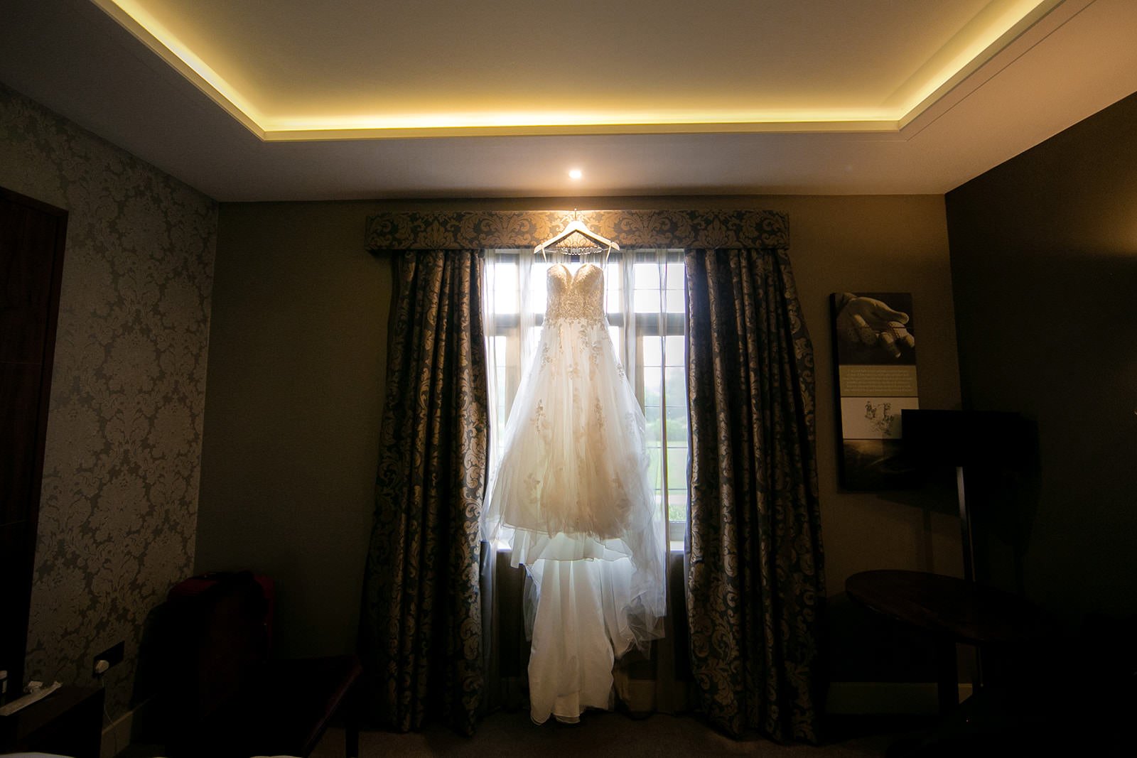 Wedding dress hanging in hotel room window at Fairmont Cheshire - The Mere

