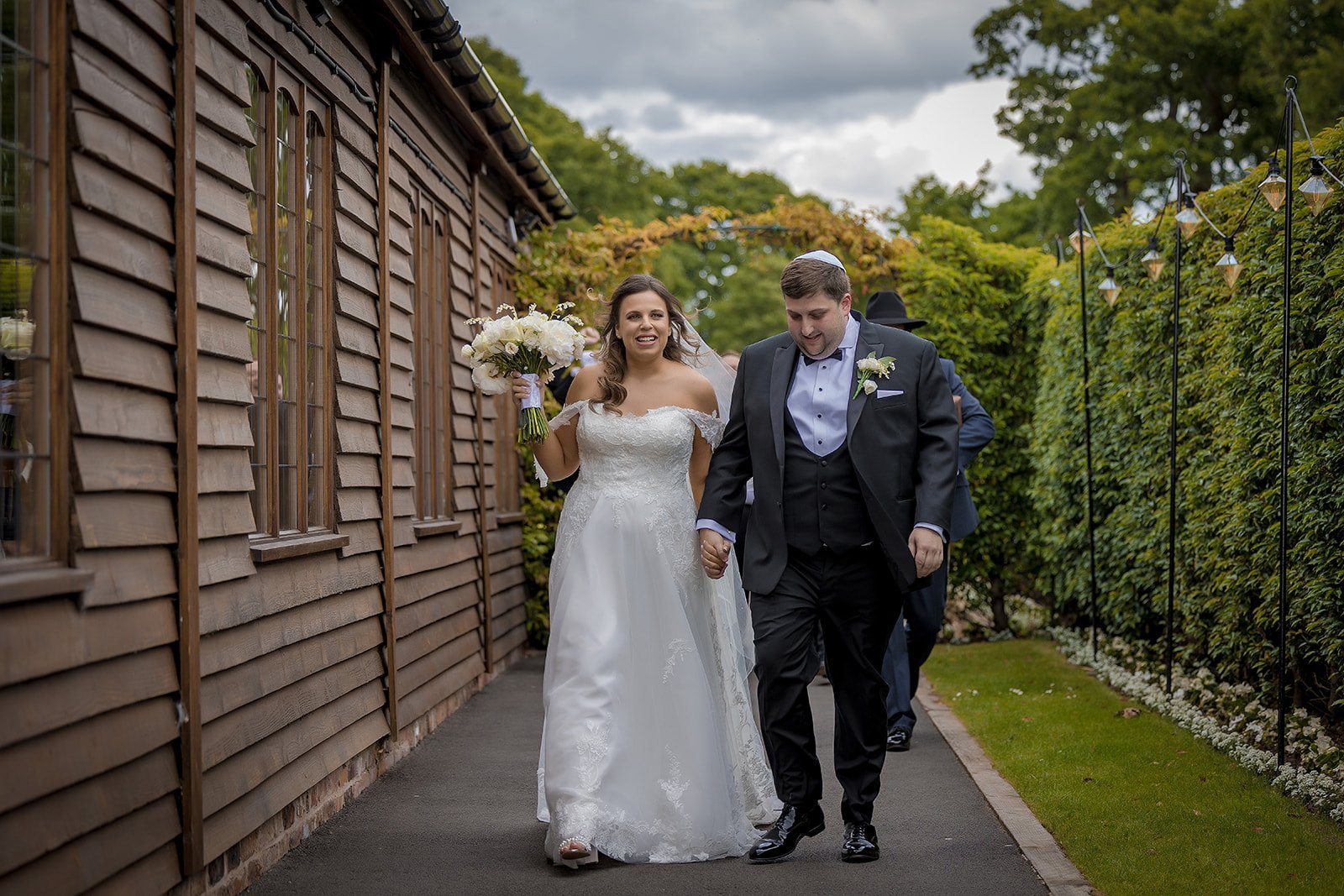 A bride and groom at Merrydale Manor holding hands and walking outdoors on their wedding day