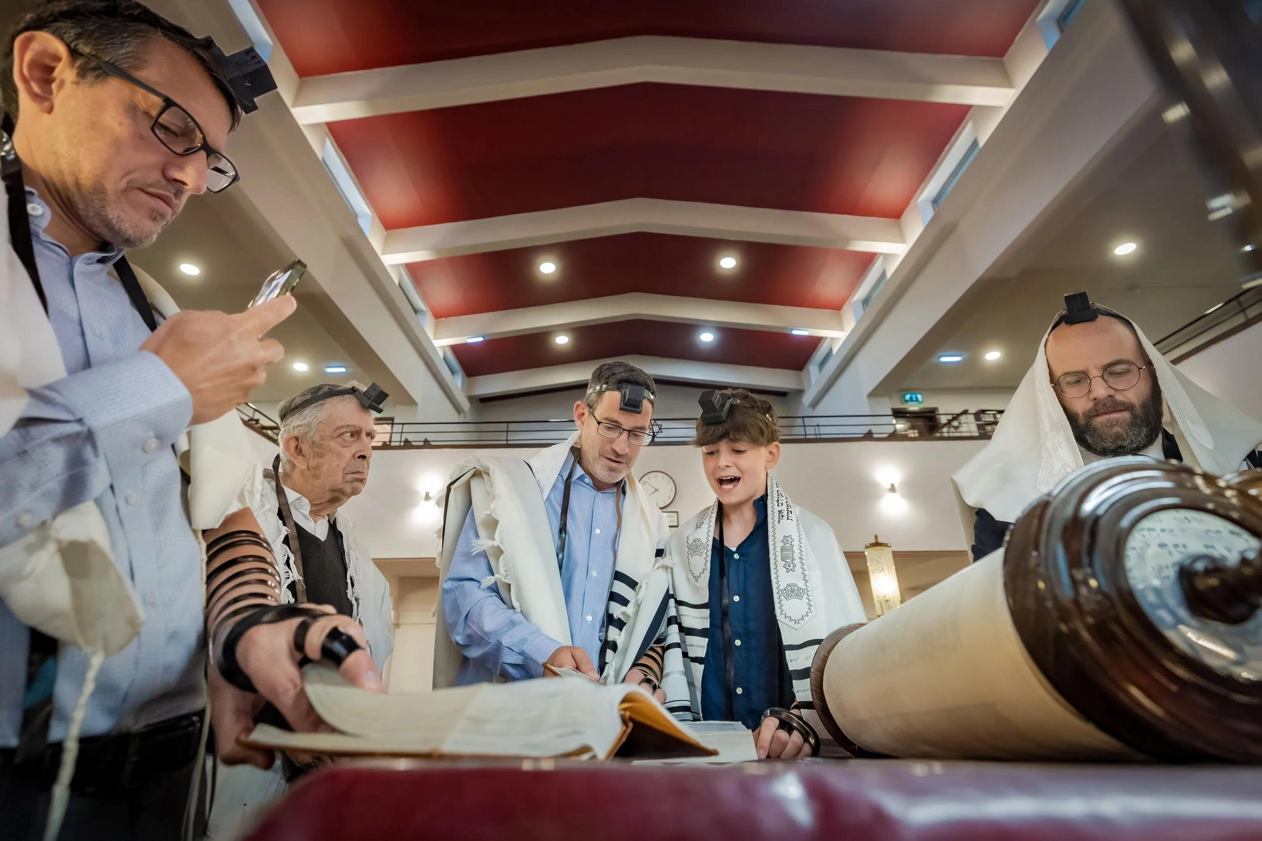 barmitzvah boy on bimah reading from torah in synagogue in Manchester with family