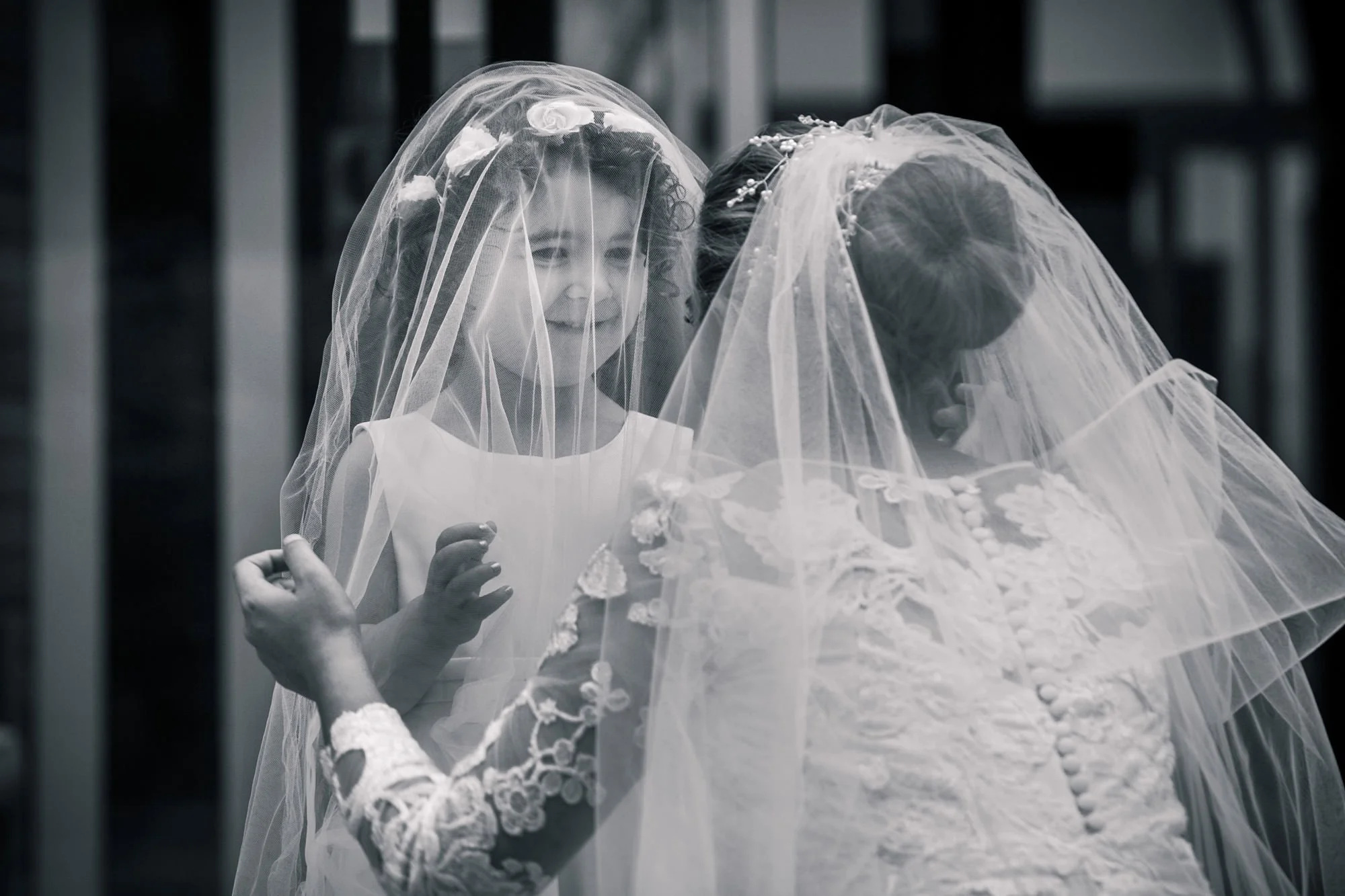 Documentary photograph of flower girl and bride playing under veil