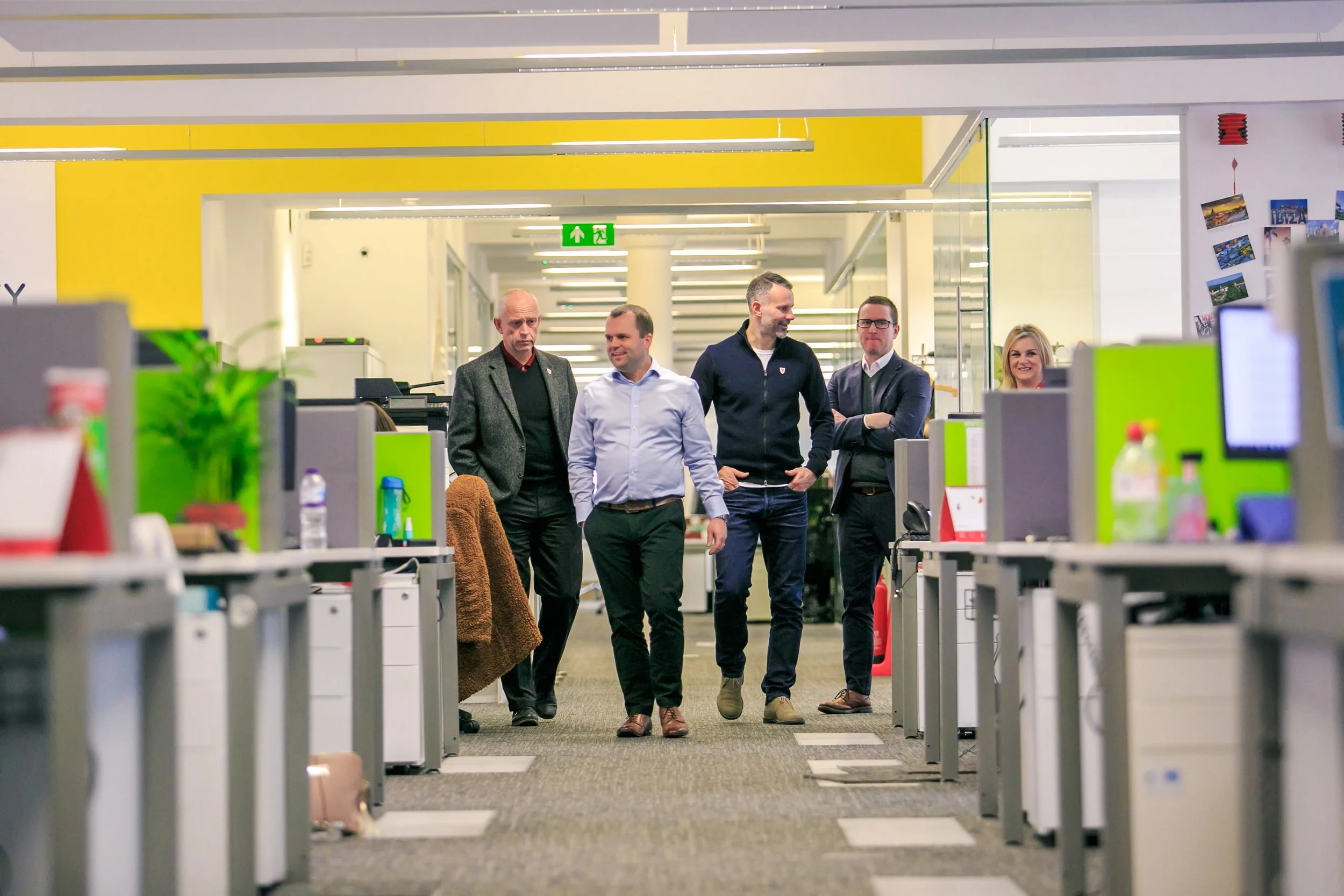 Former Manchester United footballer Ryan Giggs with business leaders walking through a modern office environment