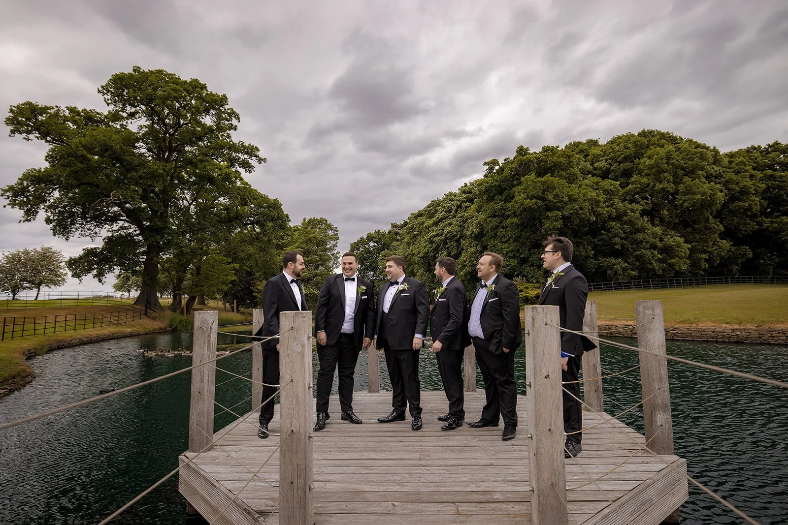 groom and groomsmen portrait on the jetty over the pond at merrydale manor wedding venue