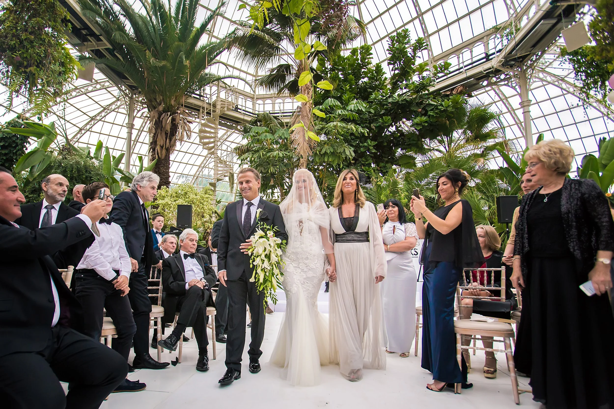 bride and parents walk down aisle at sefton park palm house wedding venue in liverpool