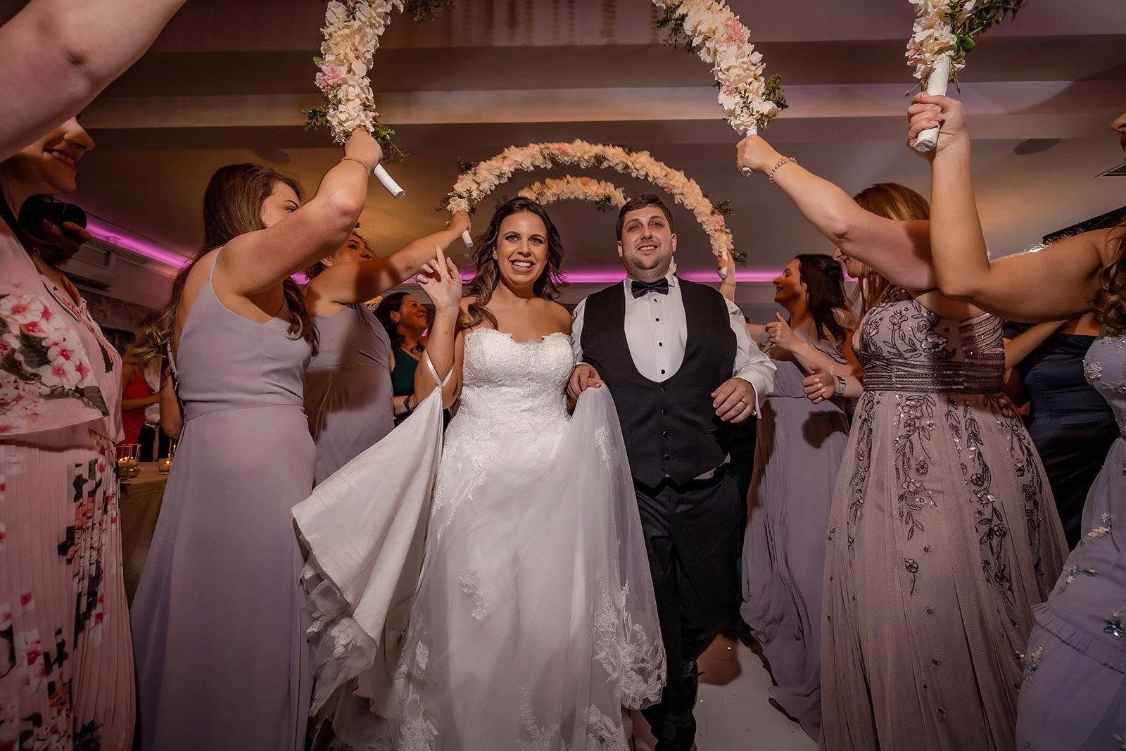 Merrydale Manor wedding couple walking under floral arch with guests – documentary wedding photography Manchester