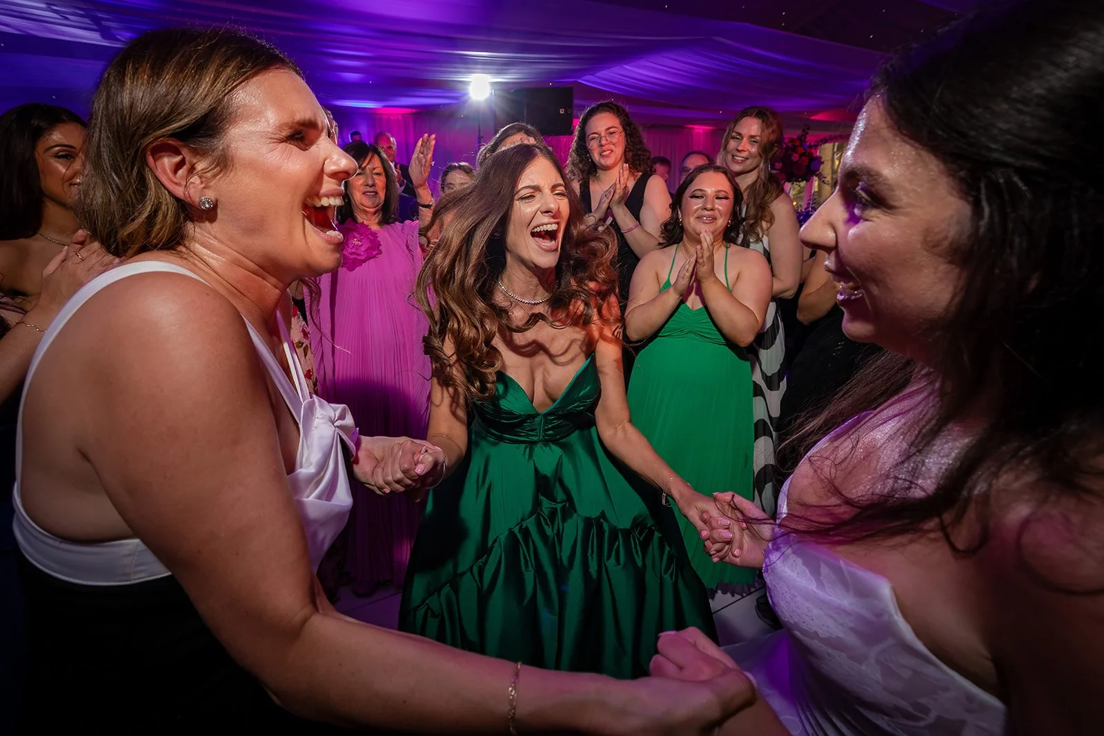 Female guests dancing and laughing under purple lighting in Nunsmere Hall marquee
