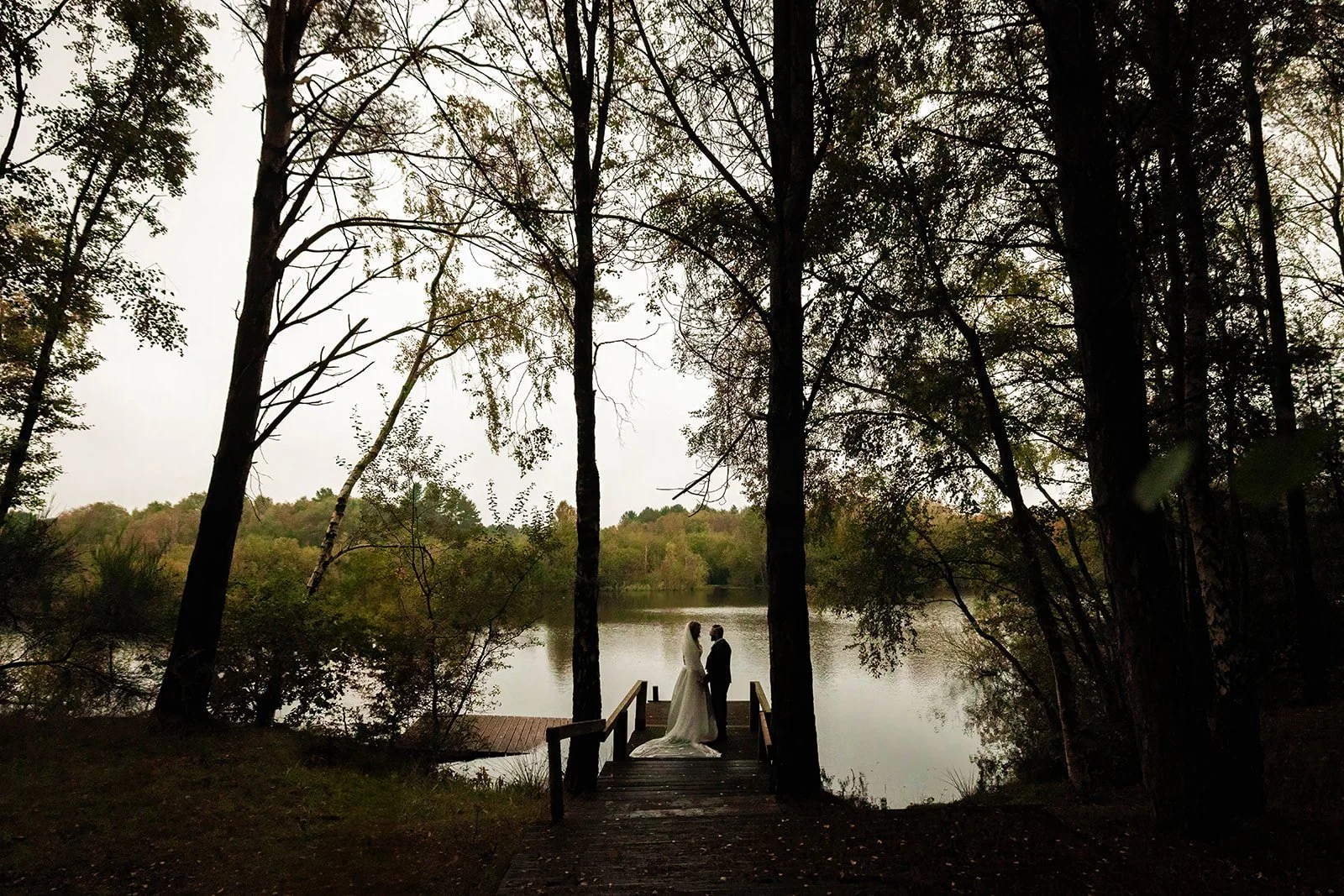 silhouette newlywed bride and groom couple portraits by lake at nunsmere hall in cheshire