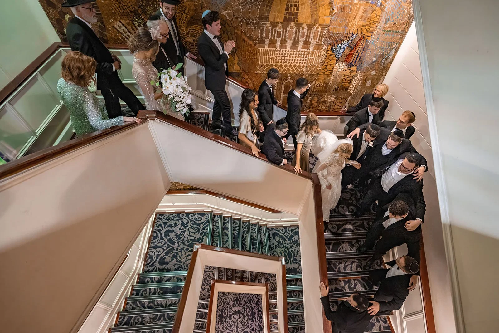 bride and groom surrounded by friends after wedding ceremony at mercure piccadilly hotel walking down stairs