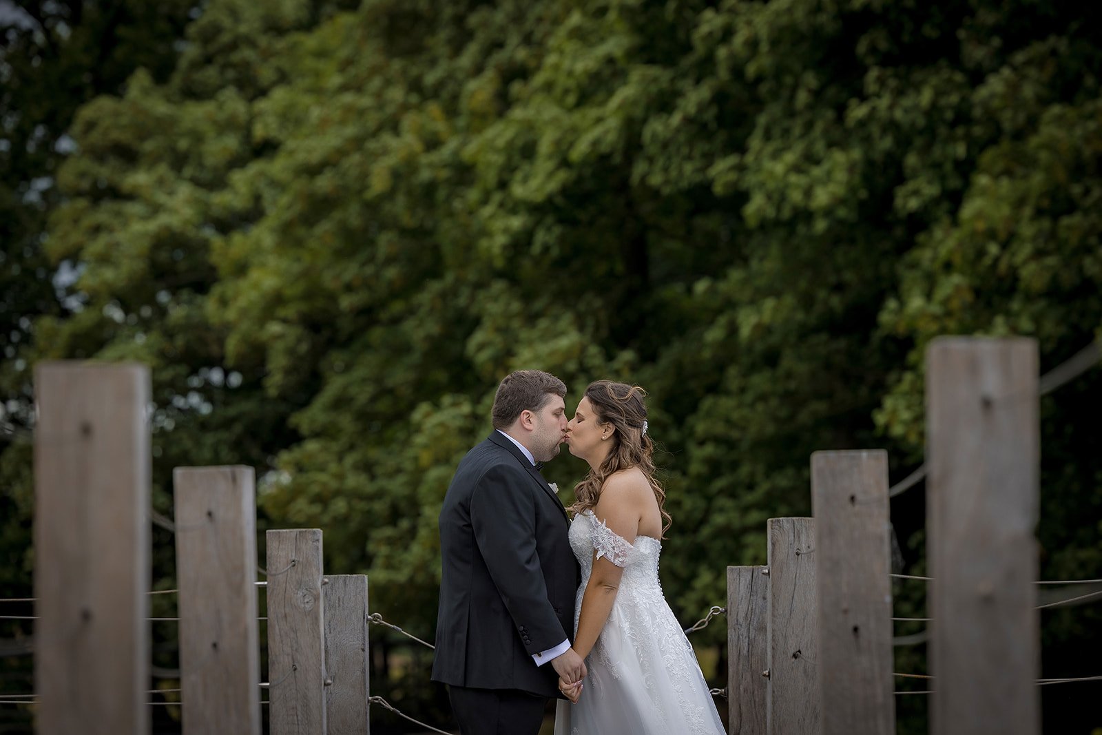 Merrydale Manor wedding couple kissing on wooden bridge in grounds – wedding photography Cheshire