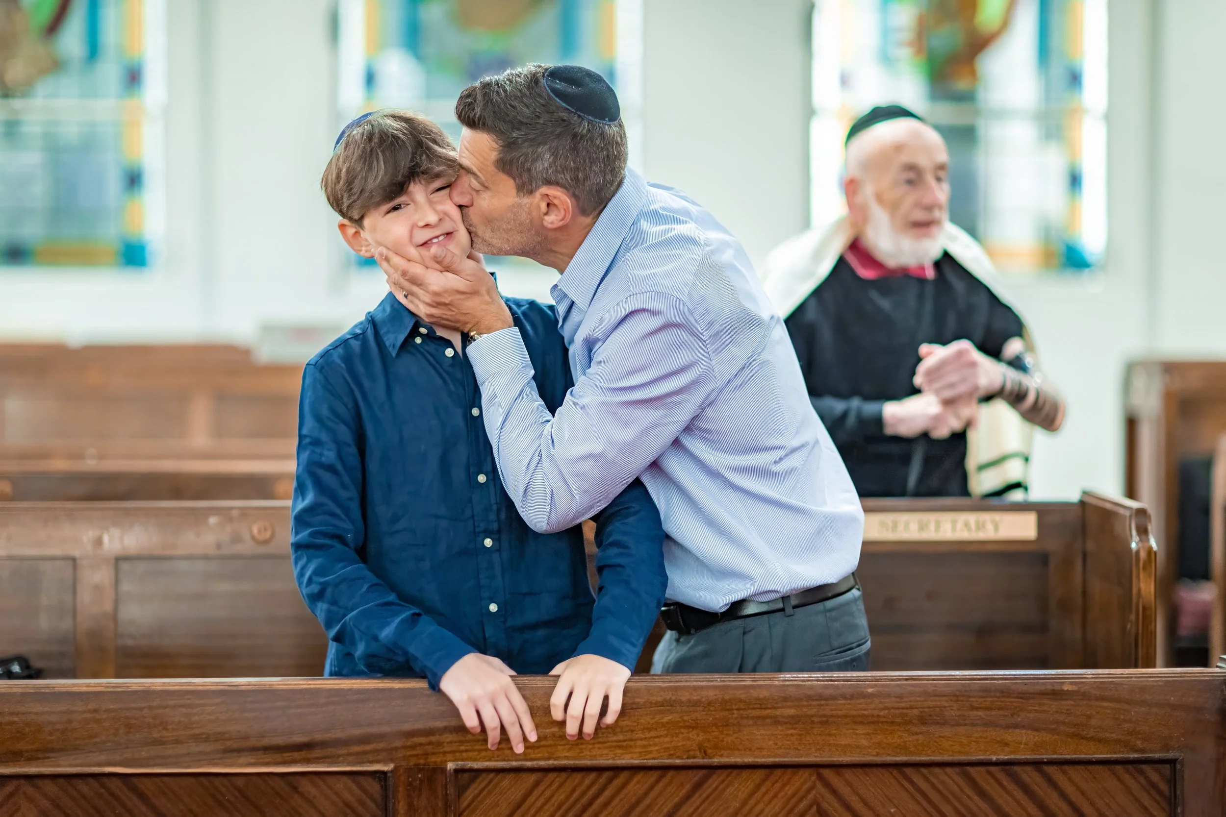 proud dad kisses barmitzvah boy in synagogue in Manchester
