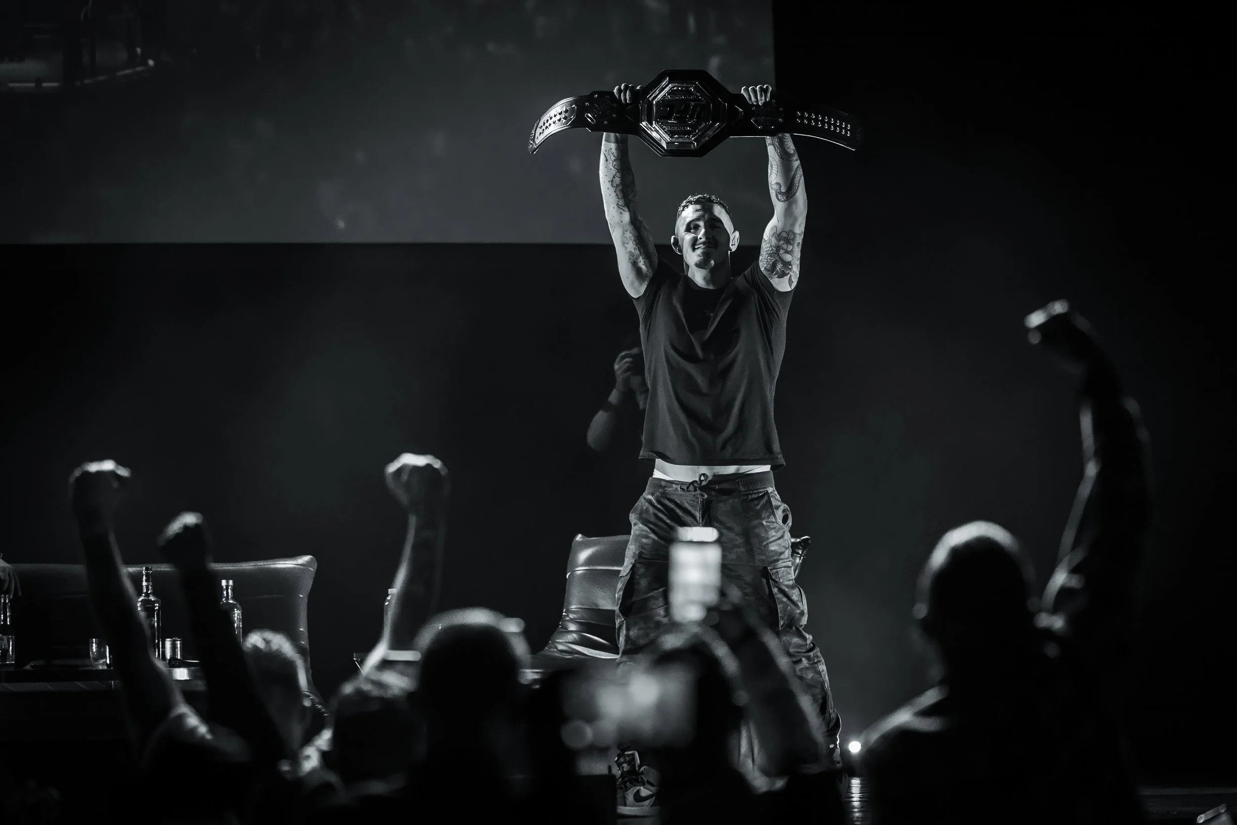 ufc heavyweight champion tom aspinal lifts belt in air on stage in front of cheering crowd in manchester