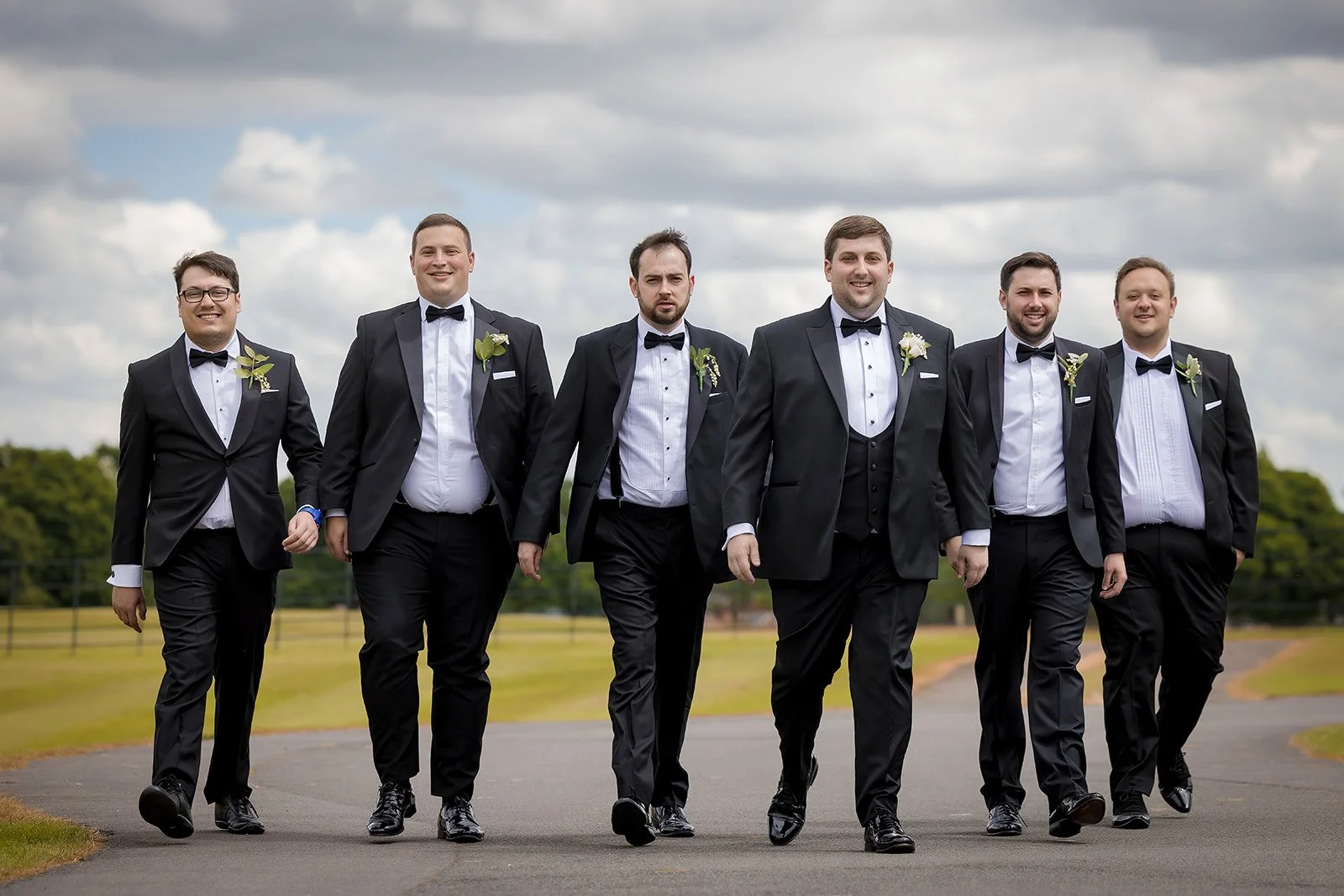 Merrydale Manor wedding groomsmen in tuxedos walking outdoors – documentary wedding photographer Manchester