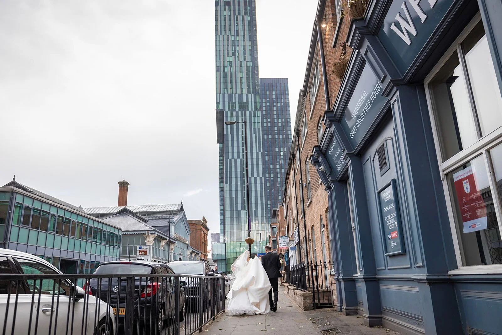 romantic newlywed bride and groom couple portrait walking towards manchester deansgate hotel