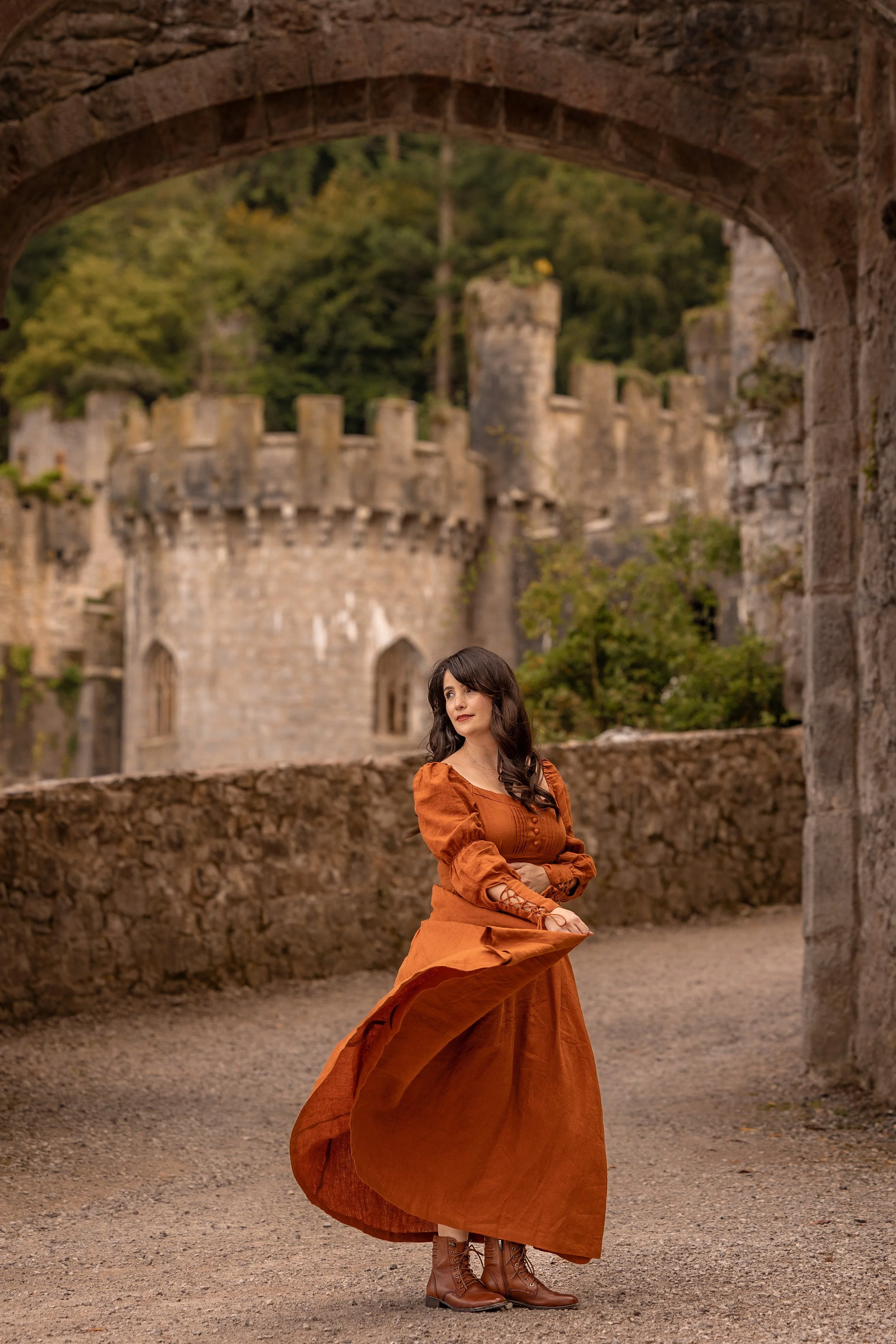 dramatic vintage female portrait in castle grounds with orange dress