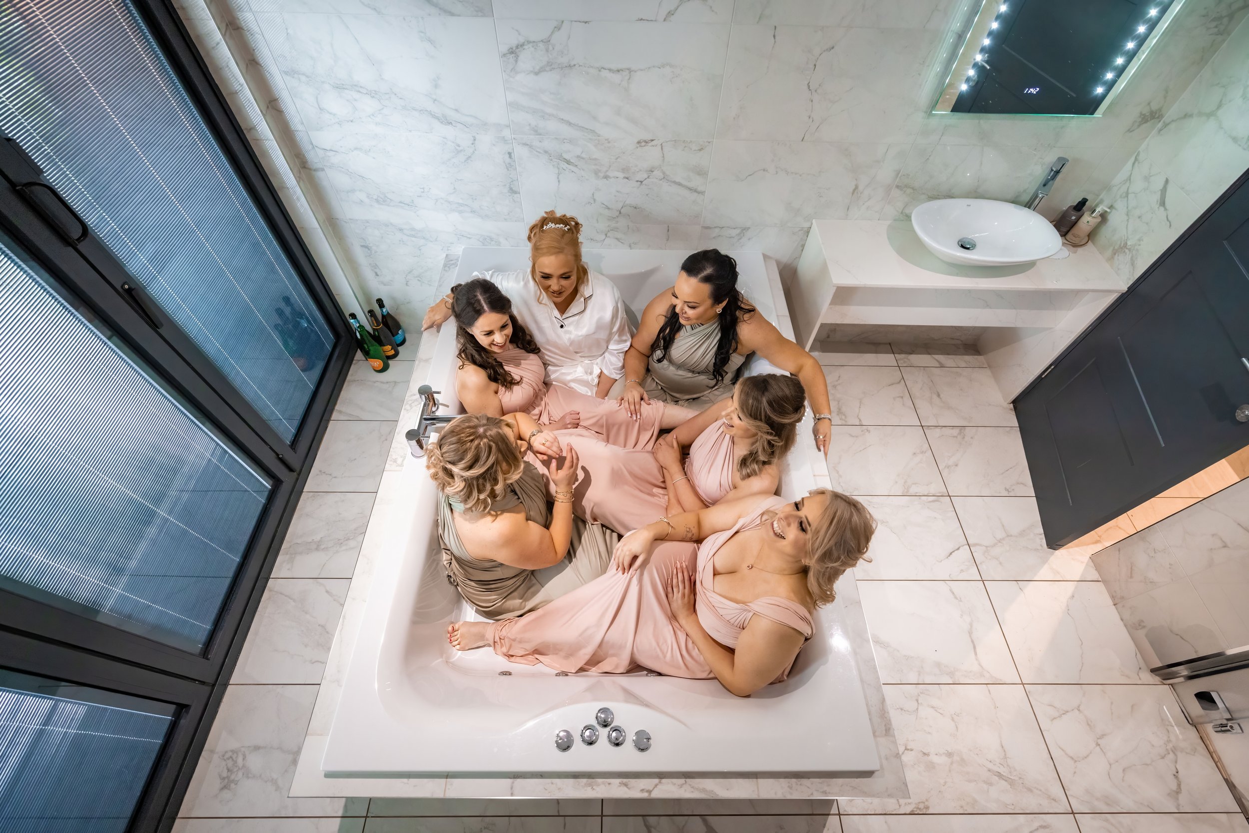 Bride and bridesmaids relaxing in a bath tub during bridal prep