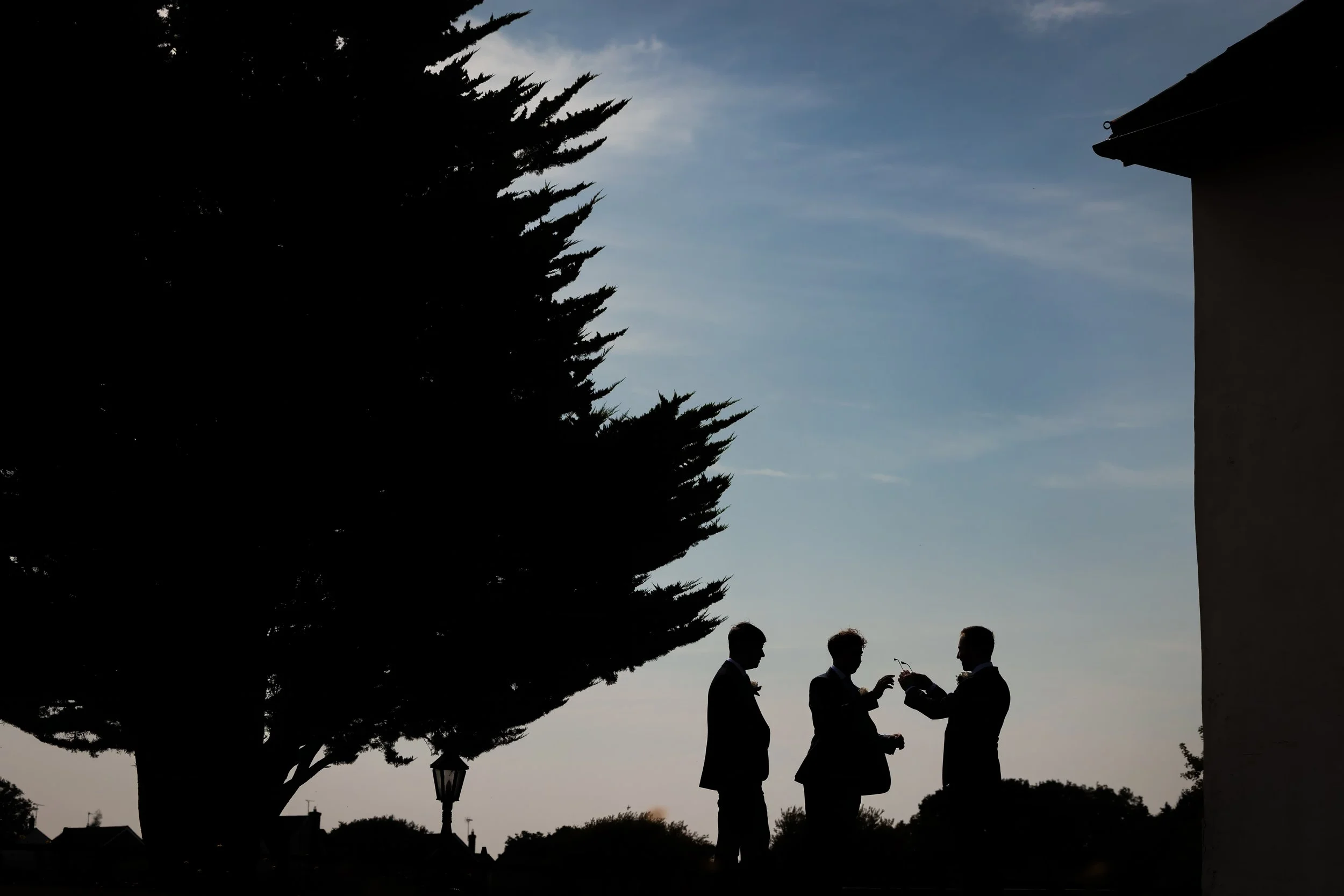 Groom and groomsmen silhouetted outdoors during wedding preparations in Manchester