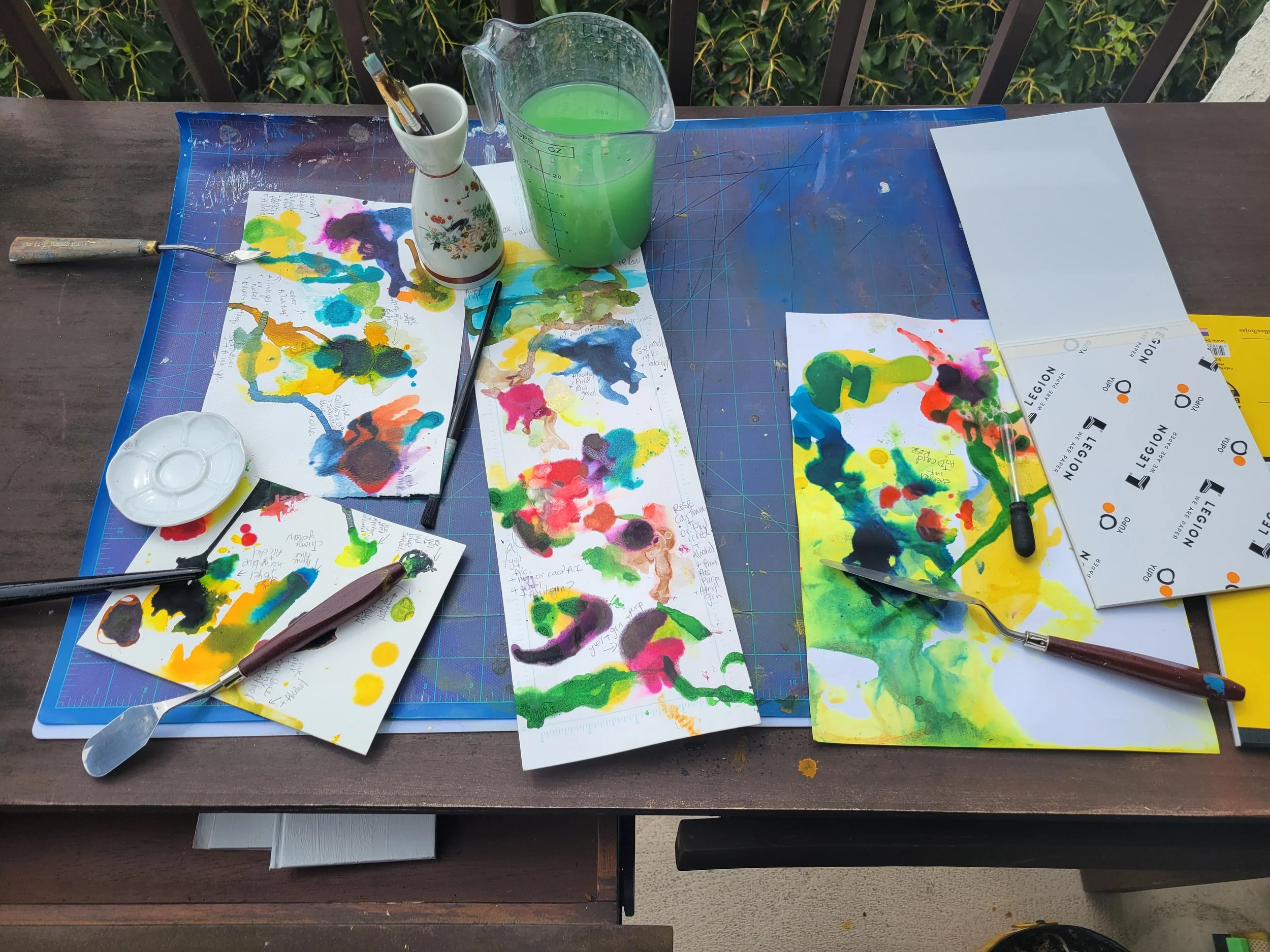 ink samples laid out on a table with a water bucket