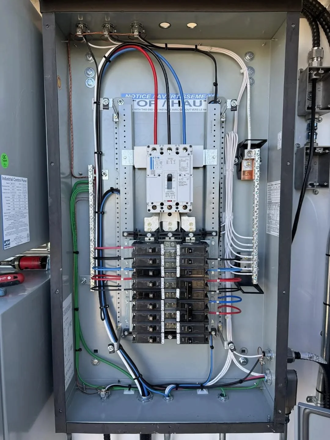 Inside an electrical control panel with various wires, circuit breakers, and components.