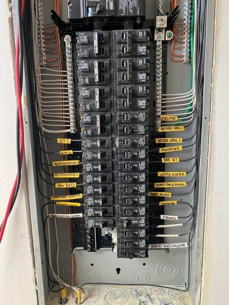 Electrical breaker box with labeled circuits for kitchen, outside grill, pantry, bar, water heater, exhaust fan, power blinds, furnace, lights, and bathroom.