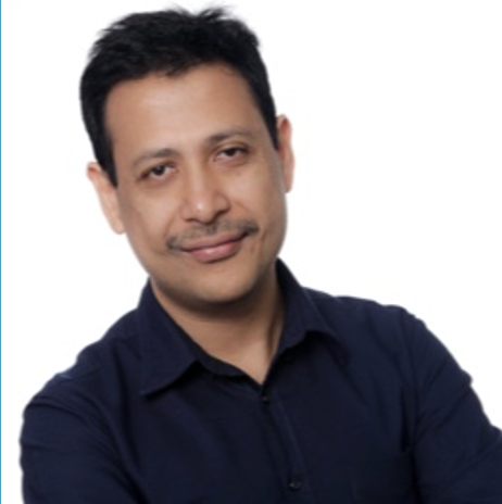 Portrait of a man with dark hair and a slight smile, wearing a dark blue shirt in front of a white background.