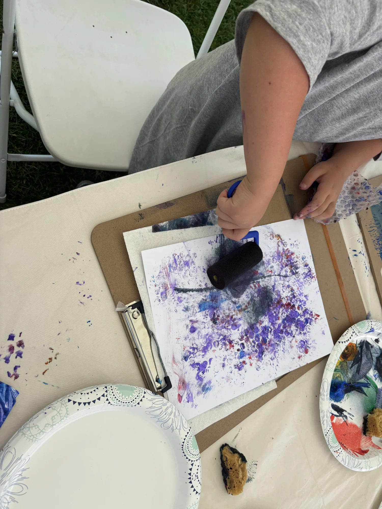 A child rolling textured purple and blue paint onto printed paper