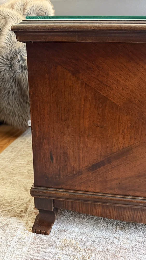Corner of a Lane cedar chest with a quarter-inch tempered glass top set inside the lid edge, diagonal veneer, and a carved foot