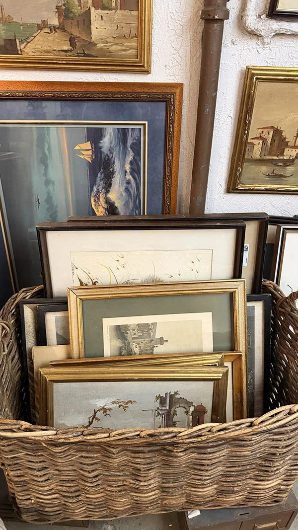 Small vintage picture frames with worn gilding and chipped corners in a wicker basket