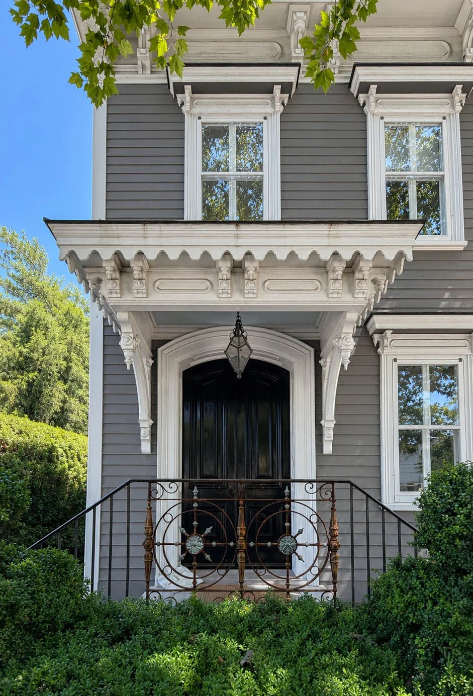 Moody entryway decor with a black lacquered door and rusted wrought iron gate, Sag Harbor front entrance