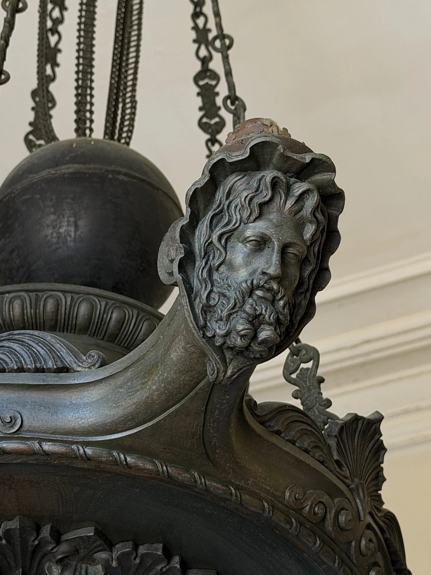 Detail of a bearded face carved into the bronze arm of an antique chandelier at the Aiken-Rhett House