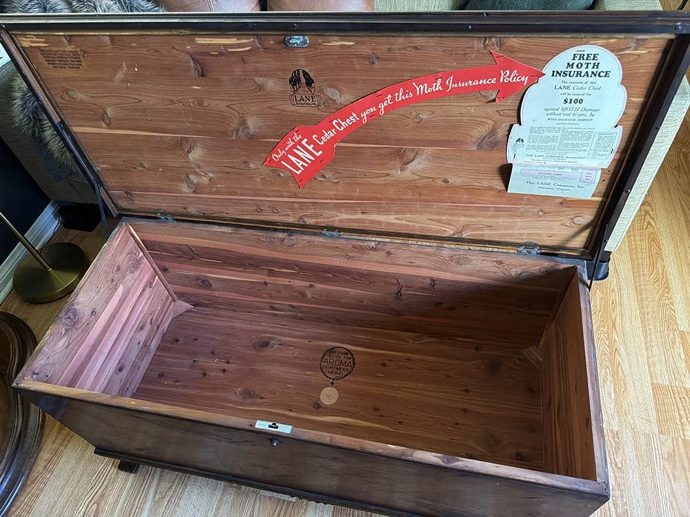 Open Lane cedar chest showing the red cedar interior, the Lane logo, and original moth insurance labels inside the lid