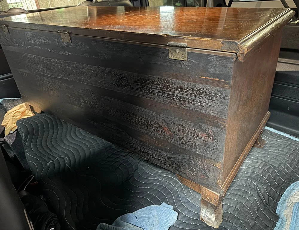 Dark textured back panel and brass hinges of a vintage Lane cedar chest