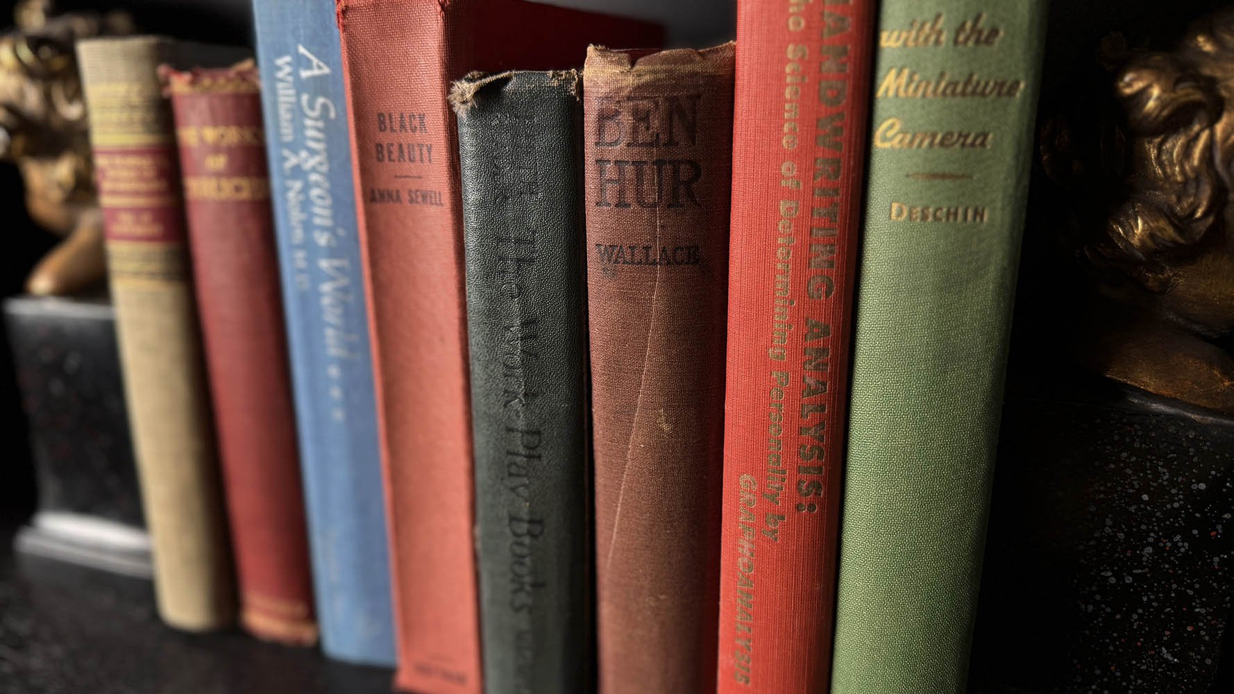 Vintage book spines including Ben Hur and Black Beauty flanked by brass bust bookends