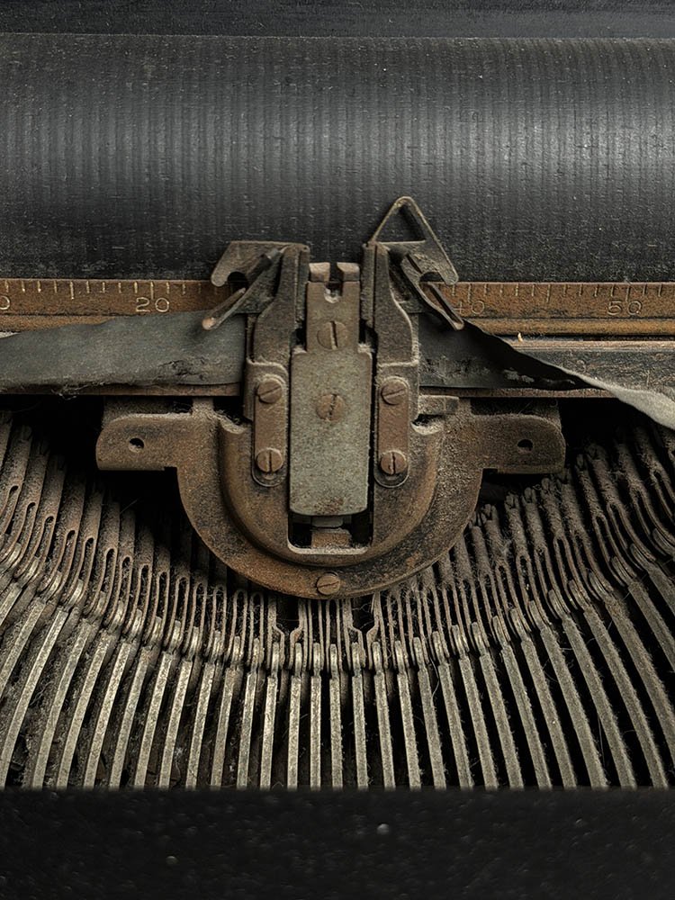 Macro detail of an antique typewriter's carriage and type bars, showing worn metal and decades of use.
