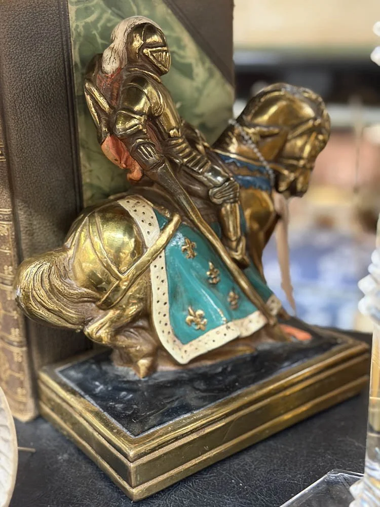 Bronze bookend of a knight on horseback with painted blue and gold armor detail.